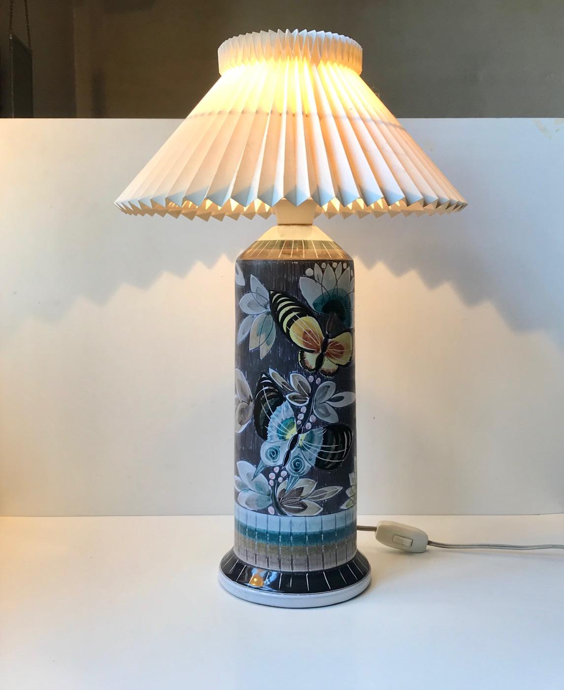 A monumental ceramic table lamp decorated with hand applied butterflies and flowers executed upon a background in sgraffito technique. It was manufactured at Alms Keramik in Gothenburg Sweden circa 1960 and it was most certainly decorated by the