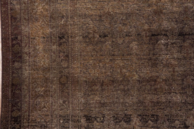 The strongly abrashed brownfield shows a row-by-row reversing allover pattern. Abrash runs from tan to umber. Brown border with a subdued floral pattern.