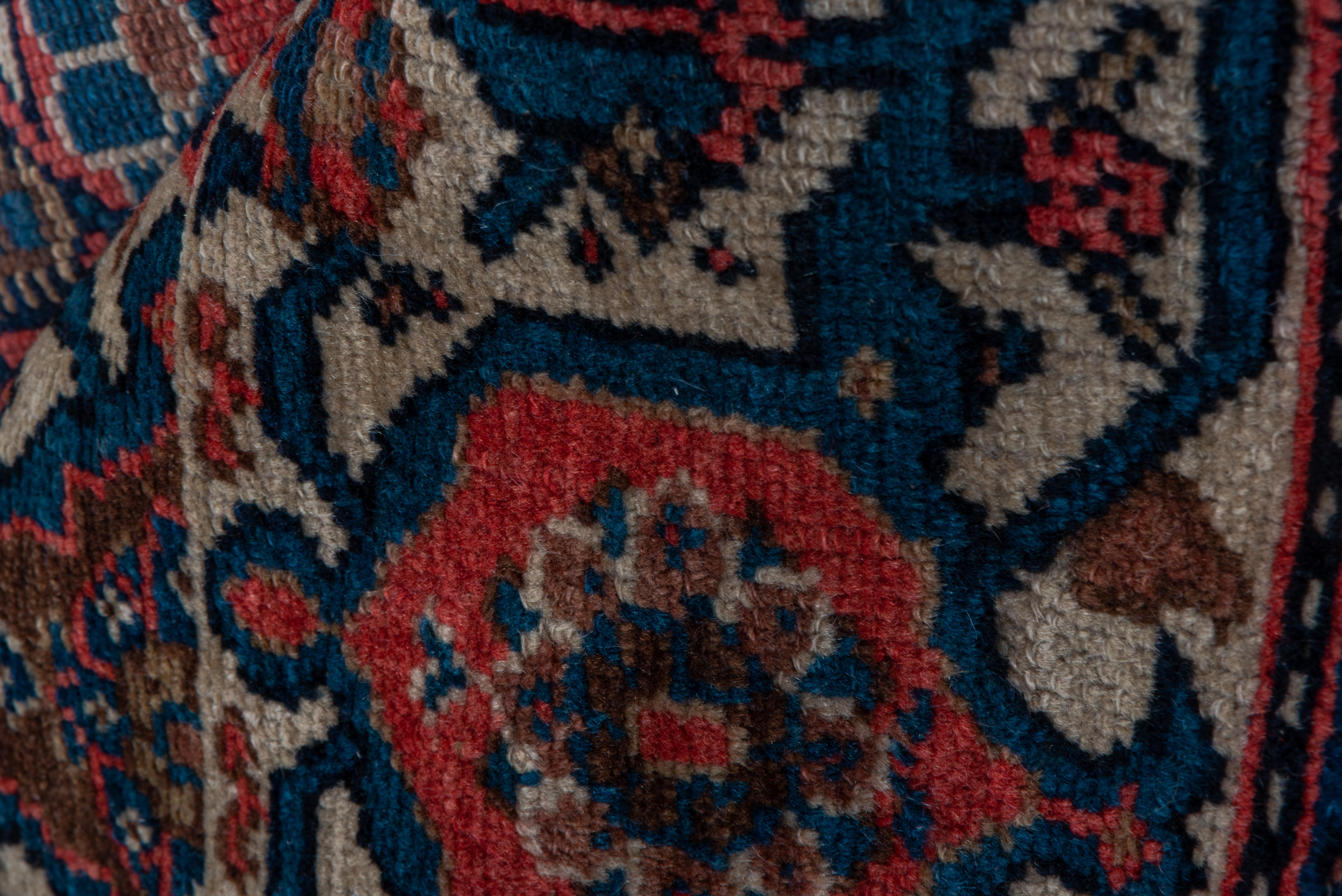 Closely set reversing floriated, open reversing boteh rows fill the notch and stepped near black subfield of this medium weave, west Persian kellegi(long rug) with red to light rose corners. Ecru main border of reversing turtle; red to minors with