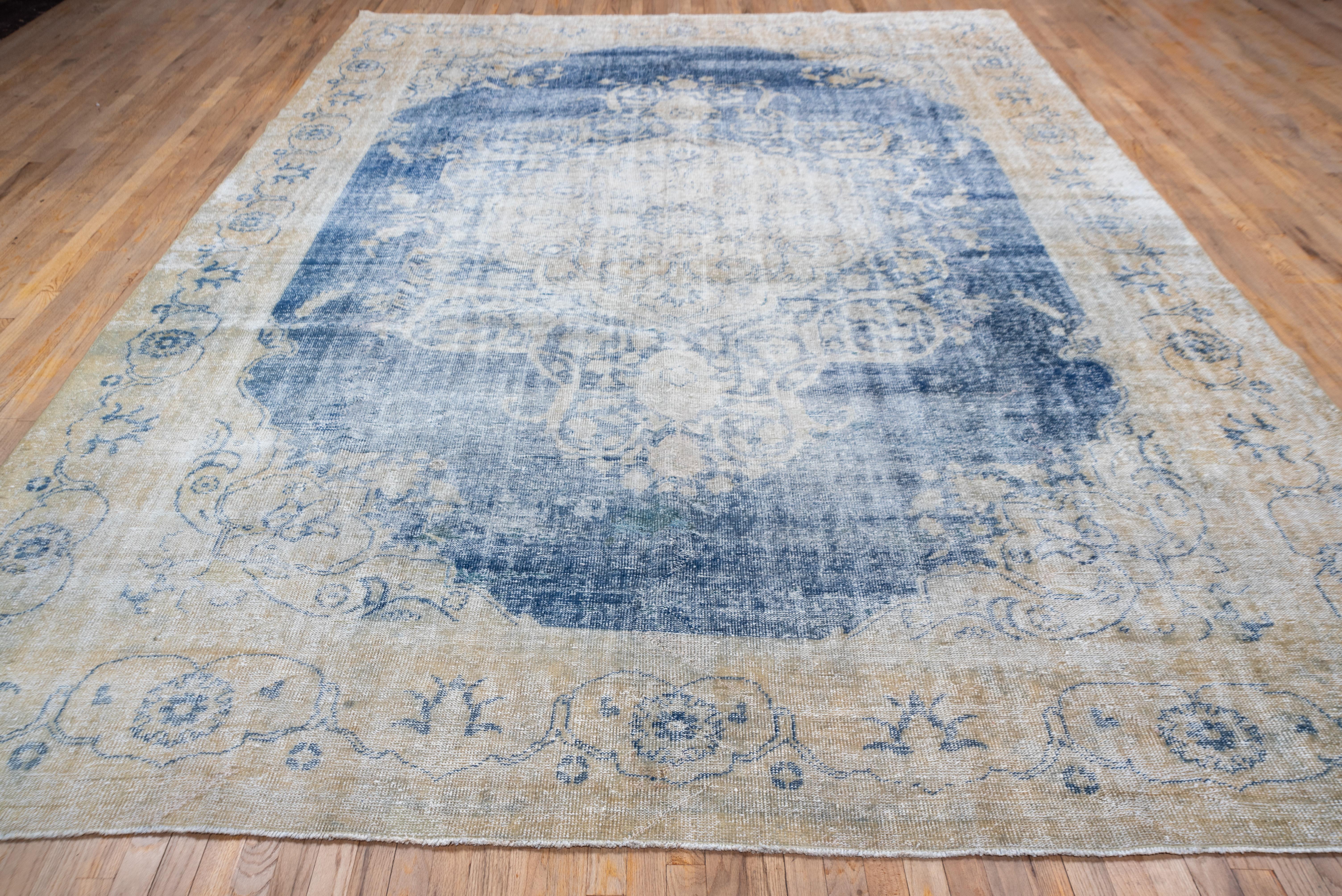 This rather distressed West Anatolian workshop carpet features a pellucid blue field centered by a cusped and pendanted straw-buff medallion with a volute arabesque surrounding wreath. Stepped arabesque and shield palmette corners. Ecru border with
