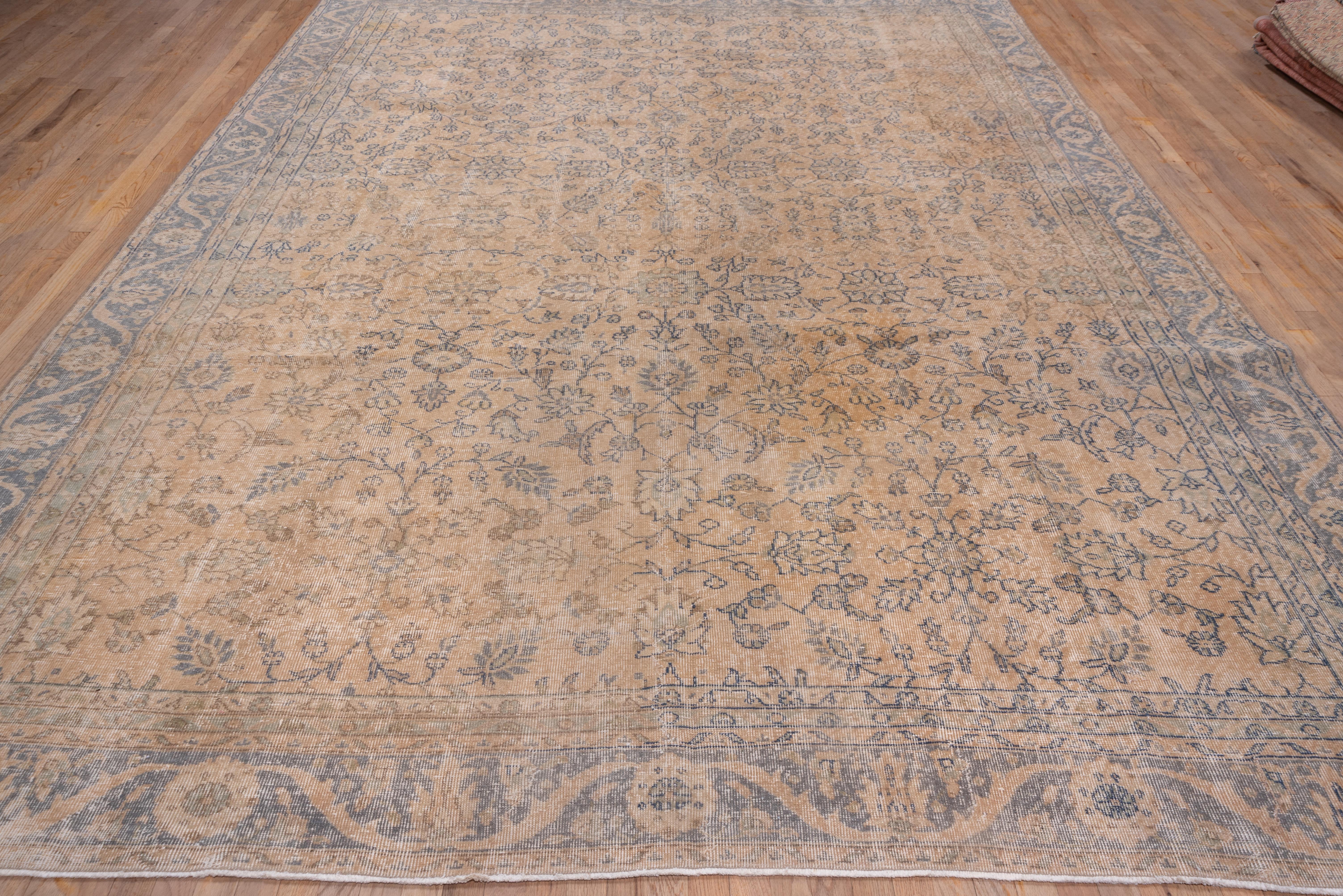 The buff field of this Turkish workshop carpet features an all-over pattern delineated in slate of rosettes, palmettes and flowering tendrils, some forming open motives. At the centre is a larger rosette sprouting palmettes. The teal grey border