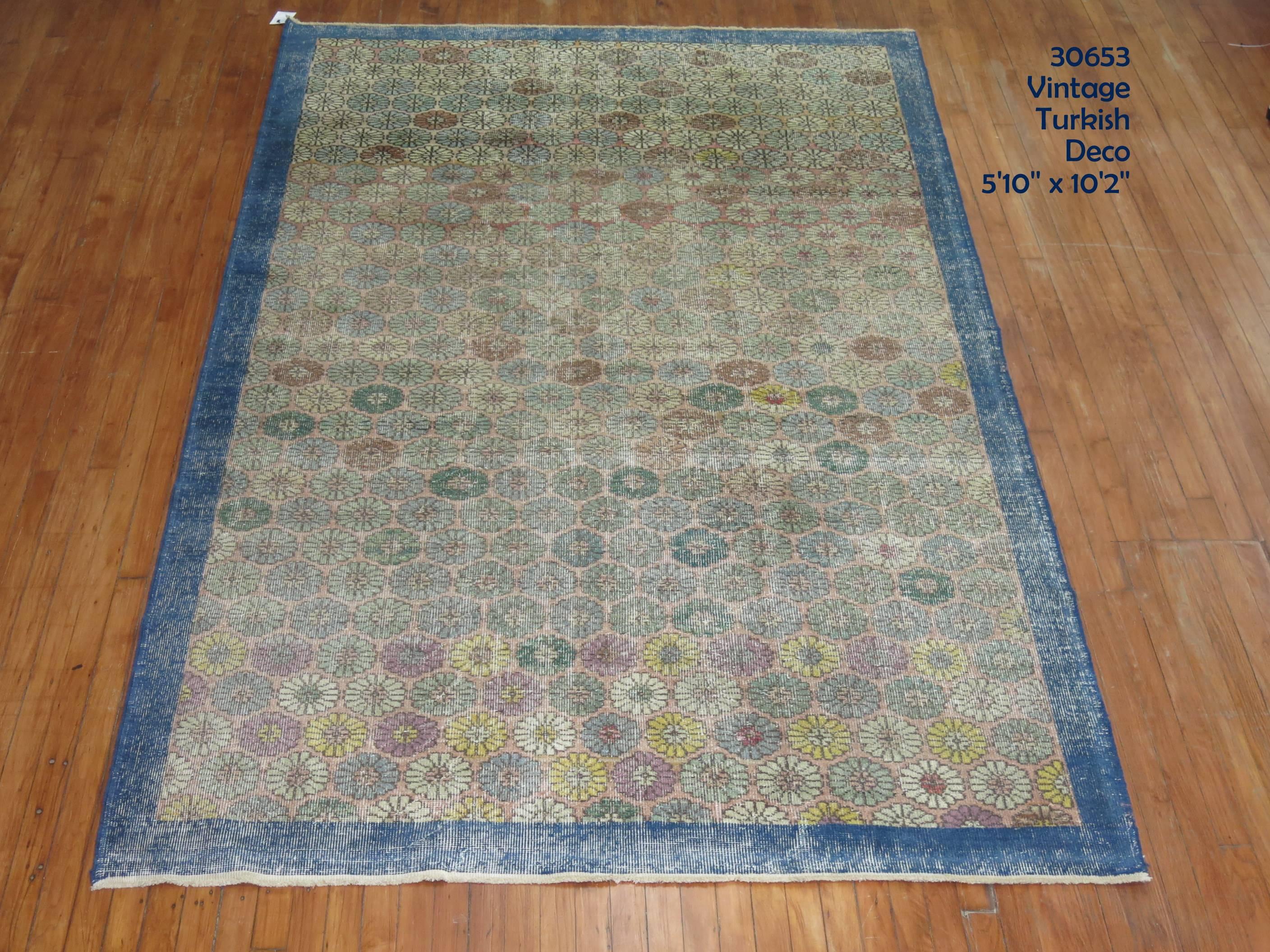 Room to intermediate size Turkish deco rug with a repetitive small floral repetitive design throughout surrounded by a denim blue bolder.

5'10'' x 10'2''