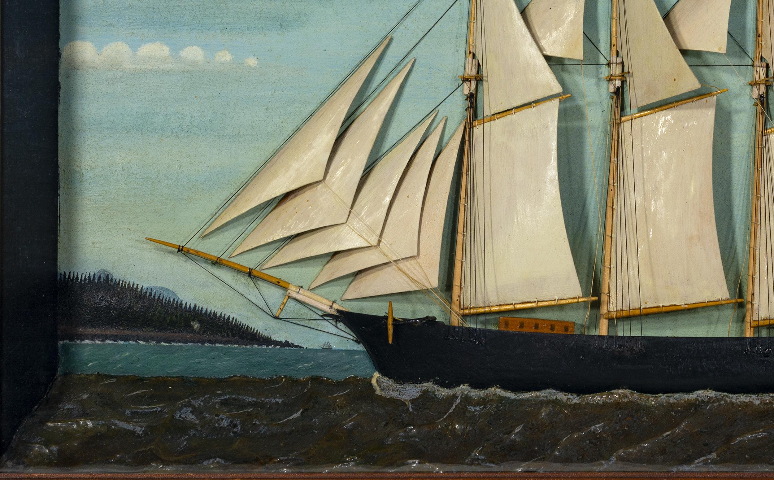 Ship diorama of a four--mast schooner with carved wooden hull, sails, masts, and accouterments, mounted in a deep mitered wood frame with painted putty sea and painted background of the sky with a shoreline and steamer in the background.