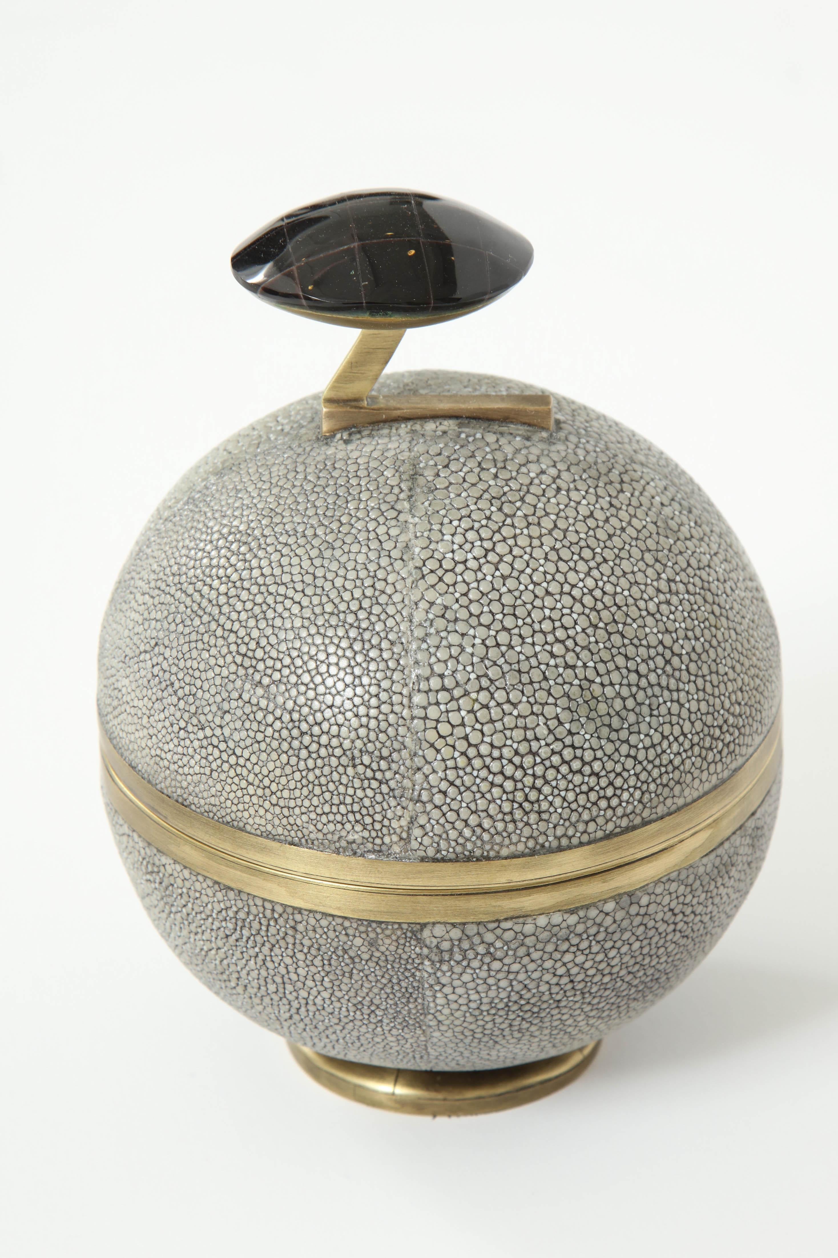 Decorative grey shagreen box with brass details and the knob is made of sea shell. Inside the box is a beautiful design with palm wood. Designed in France. 
It opens with a swirl.
Delivery time 12-14 weeks.