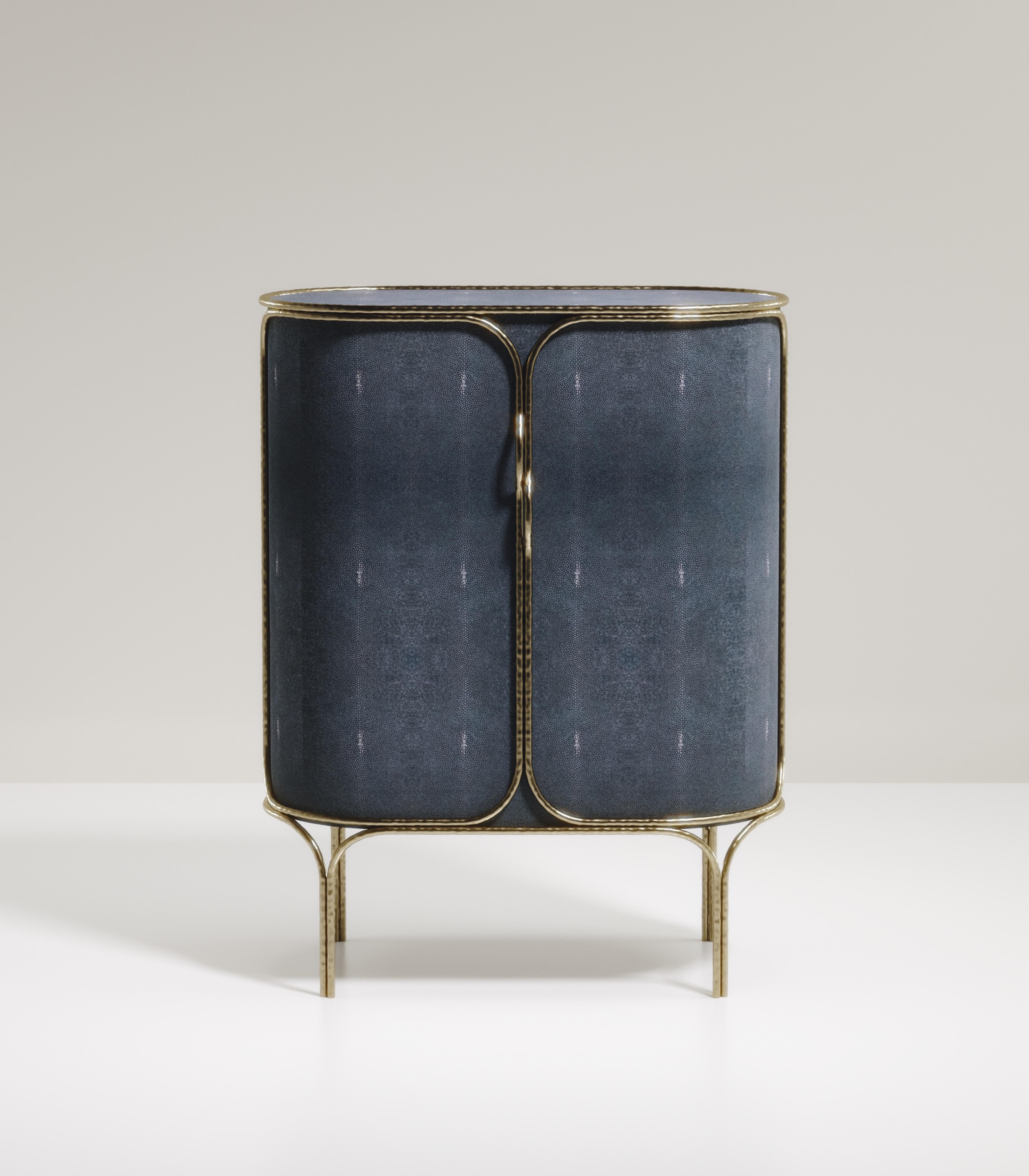 The Arianne bar Cabinet by R&Y Augousti is one of a kind statement piece. The overall piece is inlaid in a denim blue shagreen accentuated with intricate bronze-patina brass details that have the signature Augousti 