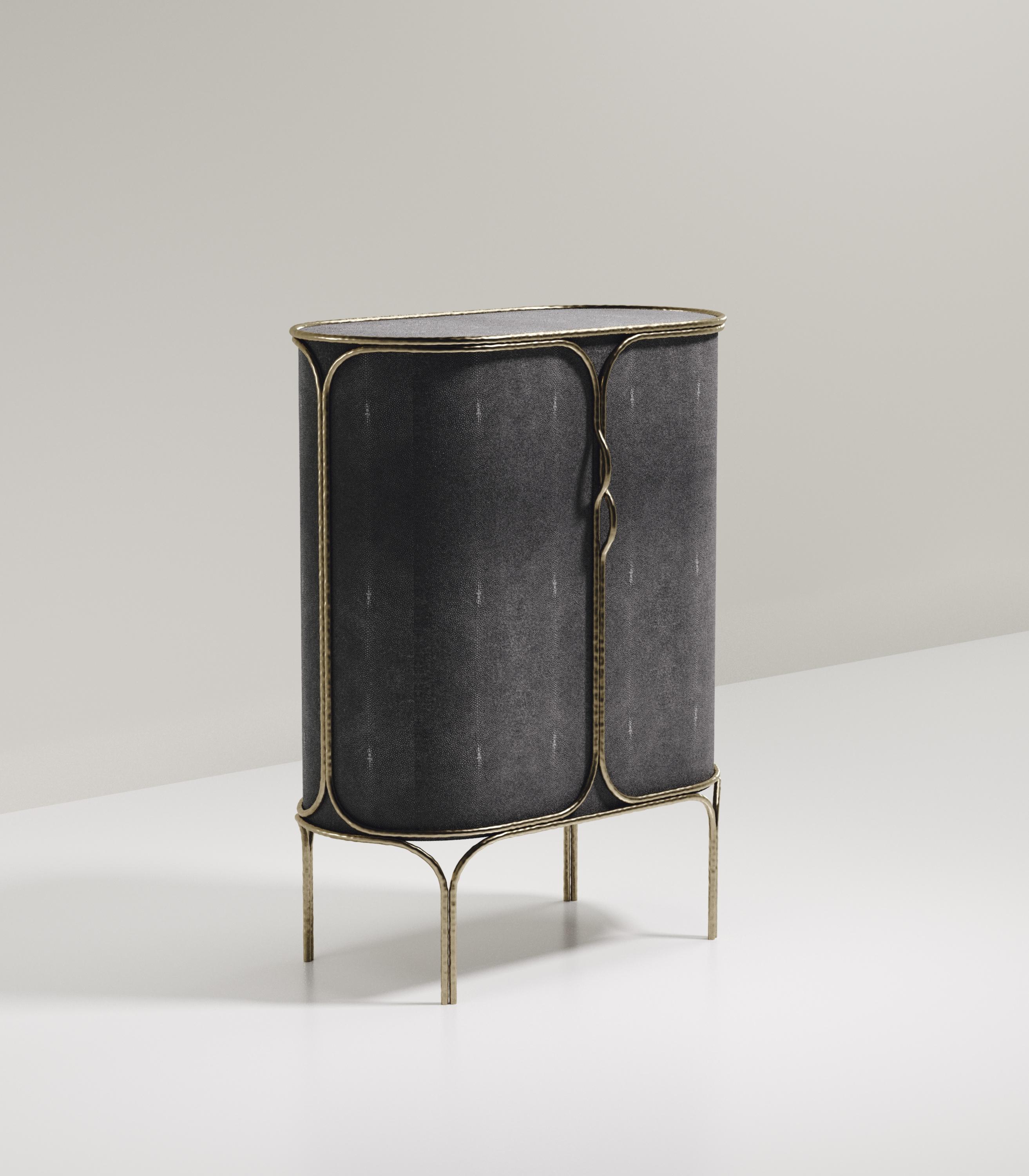 Le meuble bar Arianne de R&Y Augousti est une pièce unique. L'ensemble de la pièce est incrusté de galuchat noir de charbon, accentué par des détails complexes en laiton bronze-patine qui ont l'effet 