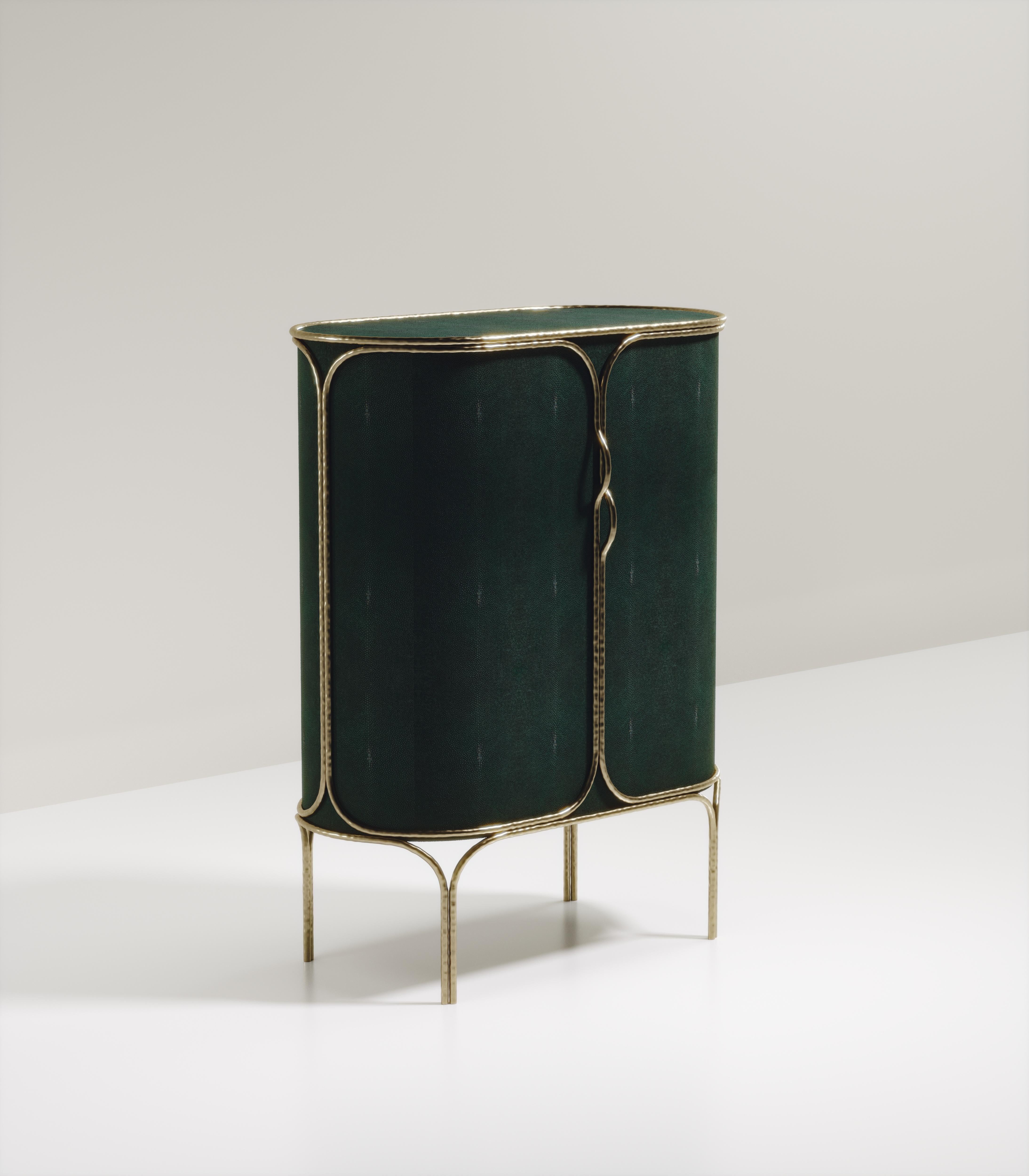 The Arianne bar cabinet by R&Y Augousti is one of a kind statement piece. The overall piece is inlaid in green shagreen accentuated with intricate bronze-patina brass details that have the signature Augousti 