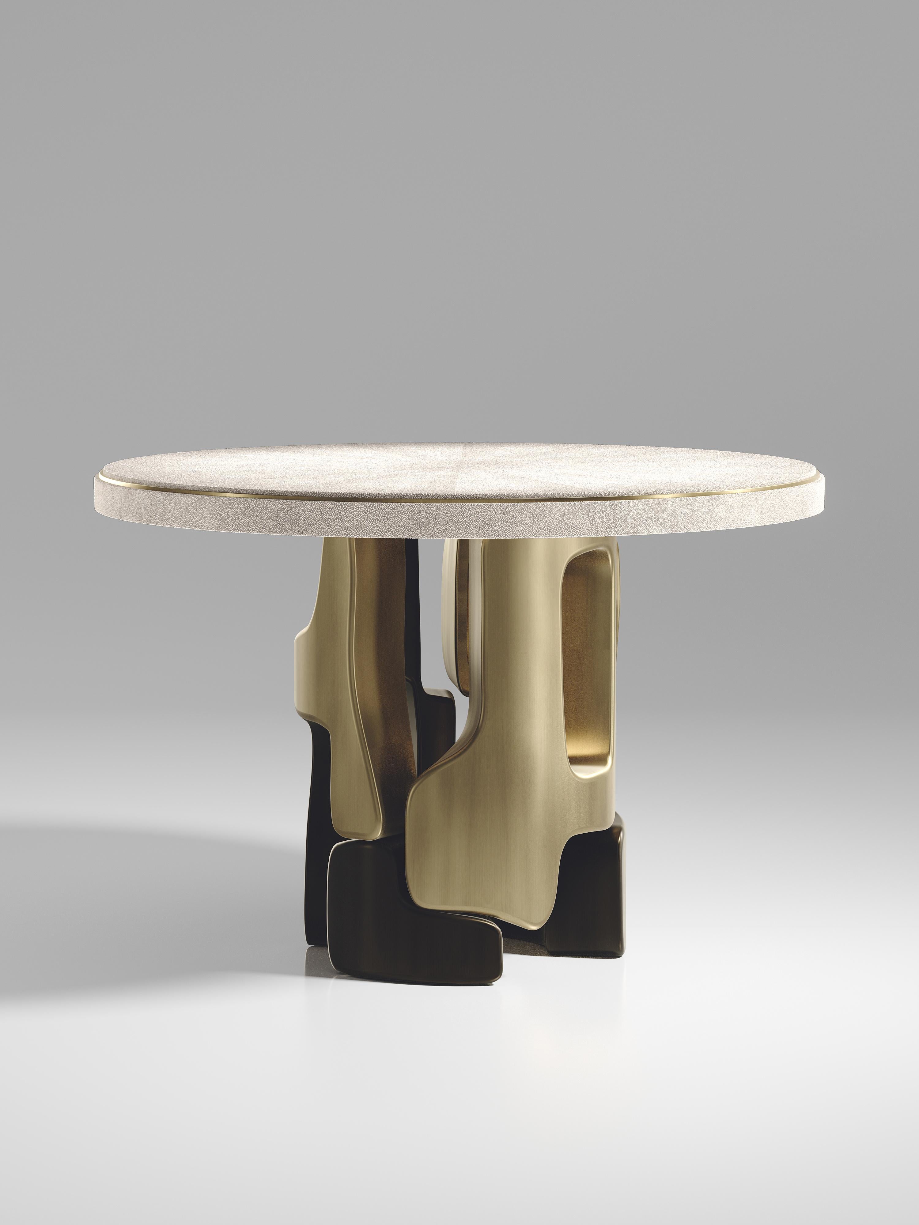 The Apoli breakfast table by Kifu Paris is both dramatic and organic its unique design. The cream shagreen inlaid top sits on an ethereal geometric and sculptural bronze-patina brass base. This piece is designed by Kifu Augousti the daughter of Ria