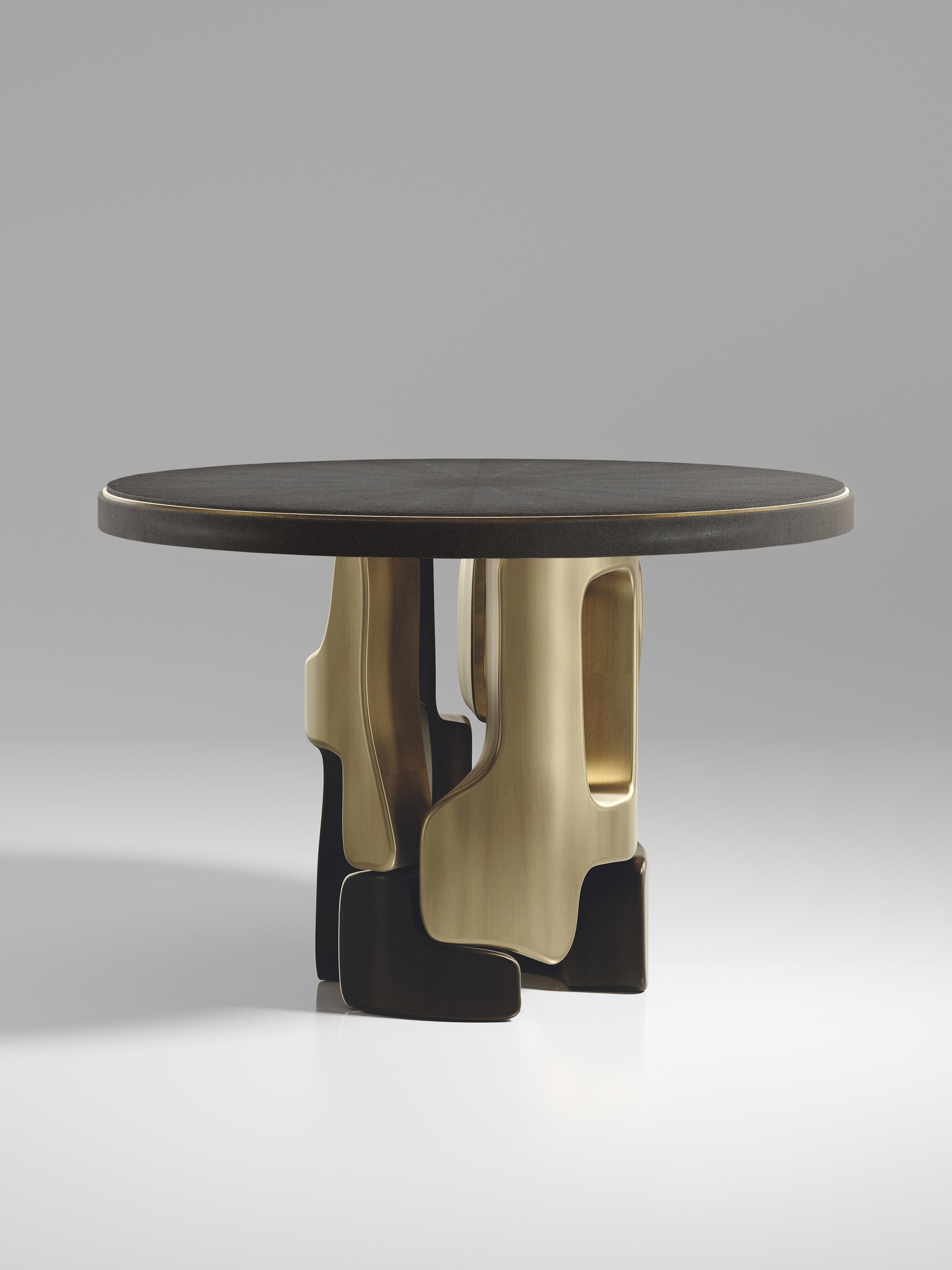 Der Frühstückstisch Apoli von Kifu Paris besticht durch sein einzigartiges Design. Die mit schwarzem Chagrin eingelegte Platte ruht auf einem geometrischen und skulpturalen Sockel aus Bronze-Patina-Messing. Dieses Stück wurde von Kifu Augousti, der