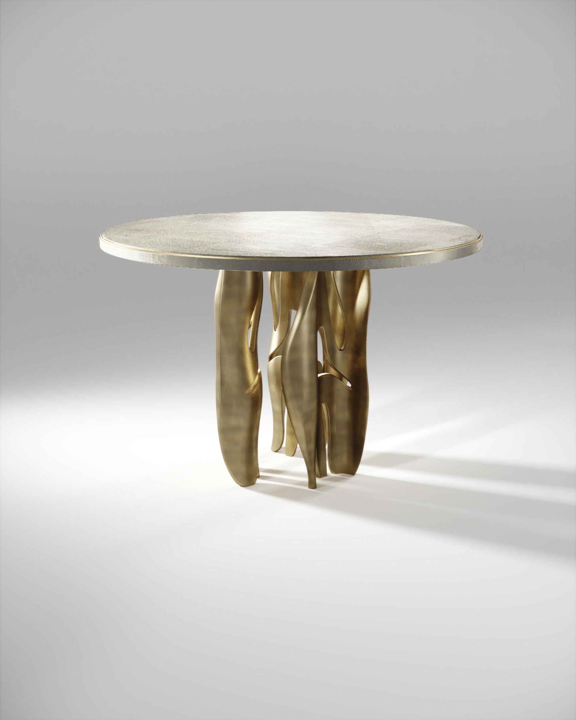 Der Frühstückstisch Metropolis II von R&Y Augousti ist ein Statement. Die runde, cremefarbene Platte mit Intarsien aus Chagrin und einer diskreten Einkerbung aus Metall steht auf einer Gruppe dramatischer, skulpturaler Beine aus