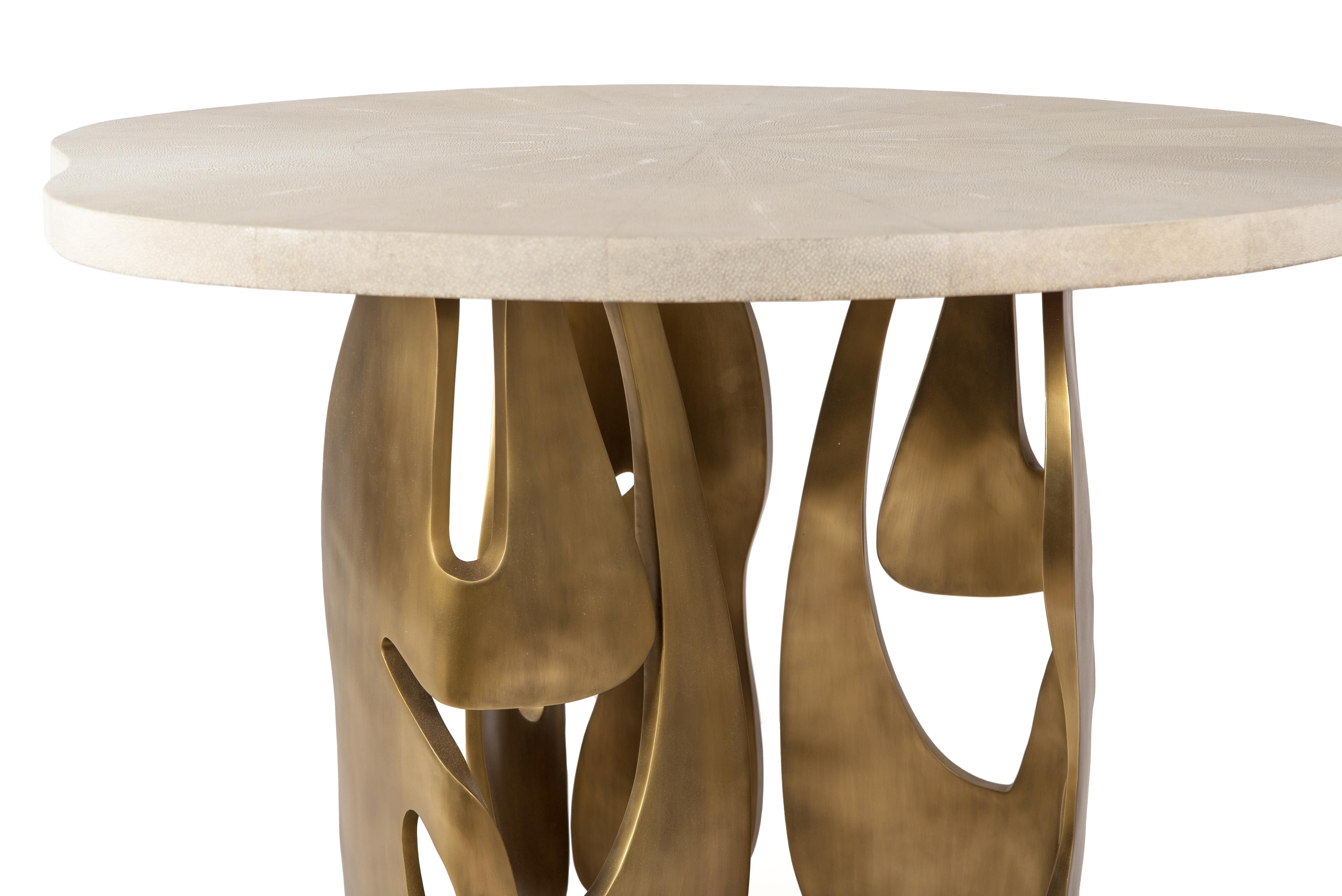 The Metropolis II breakfast table by R&Y Augousti is a statement piece. The amorphous-shaped cream shagreen inlaid top sits on a cluster of dramatic sculptural bronze-patina brass legs, showcasing the brand's incredible artisanal work. View the