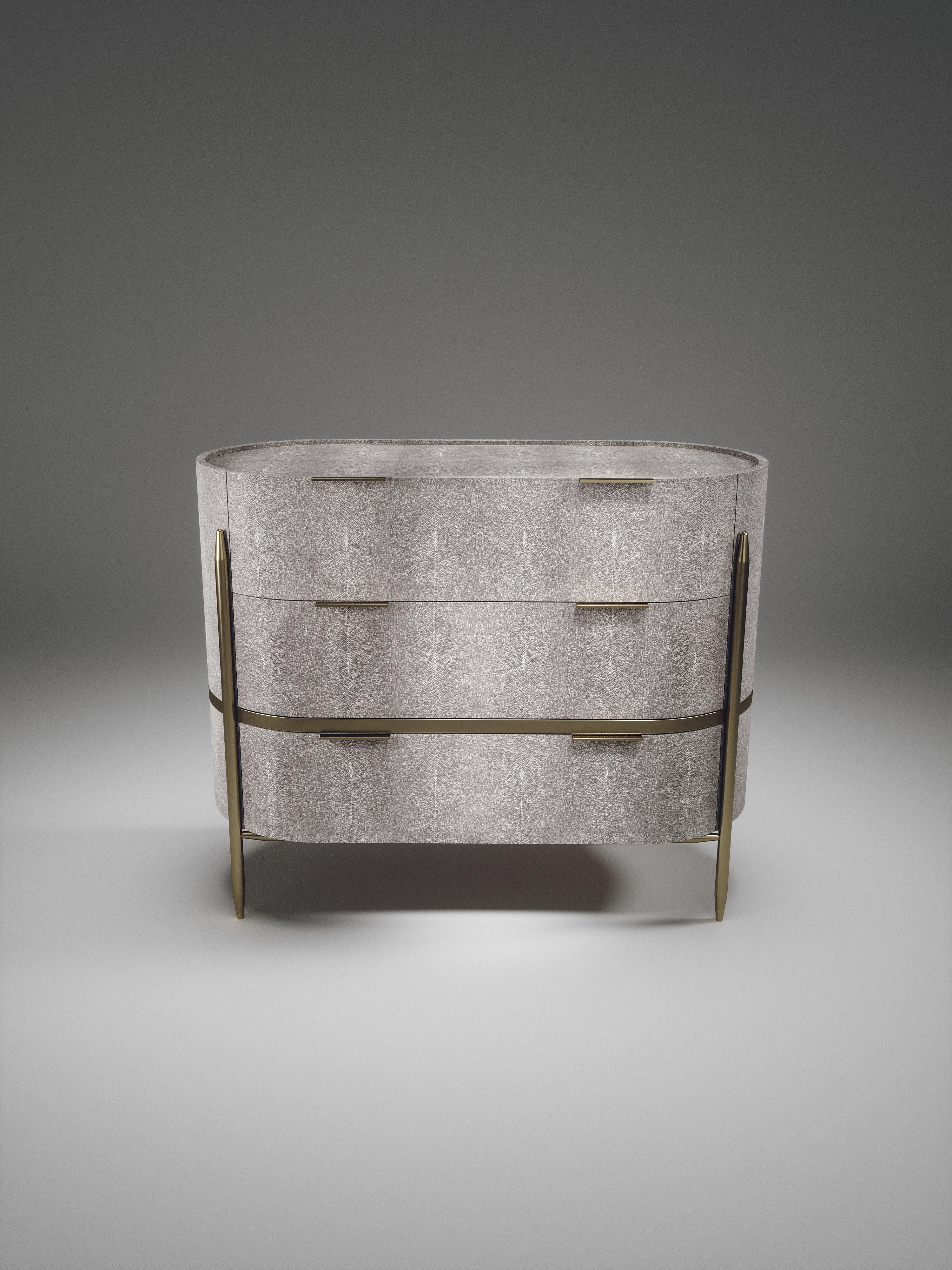 La commode ovale Dandy de Kifu Paris est un accent élégant et luxueux pour la maison, incrustée de galuchat gris clair avec des détails en laiton bronze-patiné. Cette pièce comprend 3 tiroirs au total et les intérieurs sont incrustés en placage de