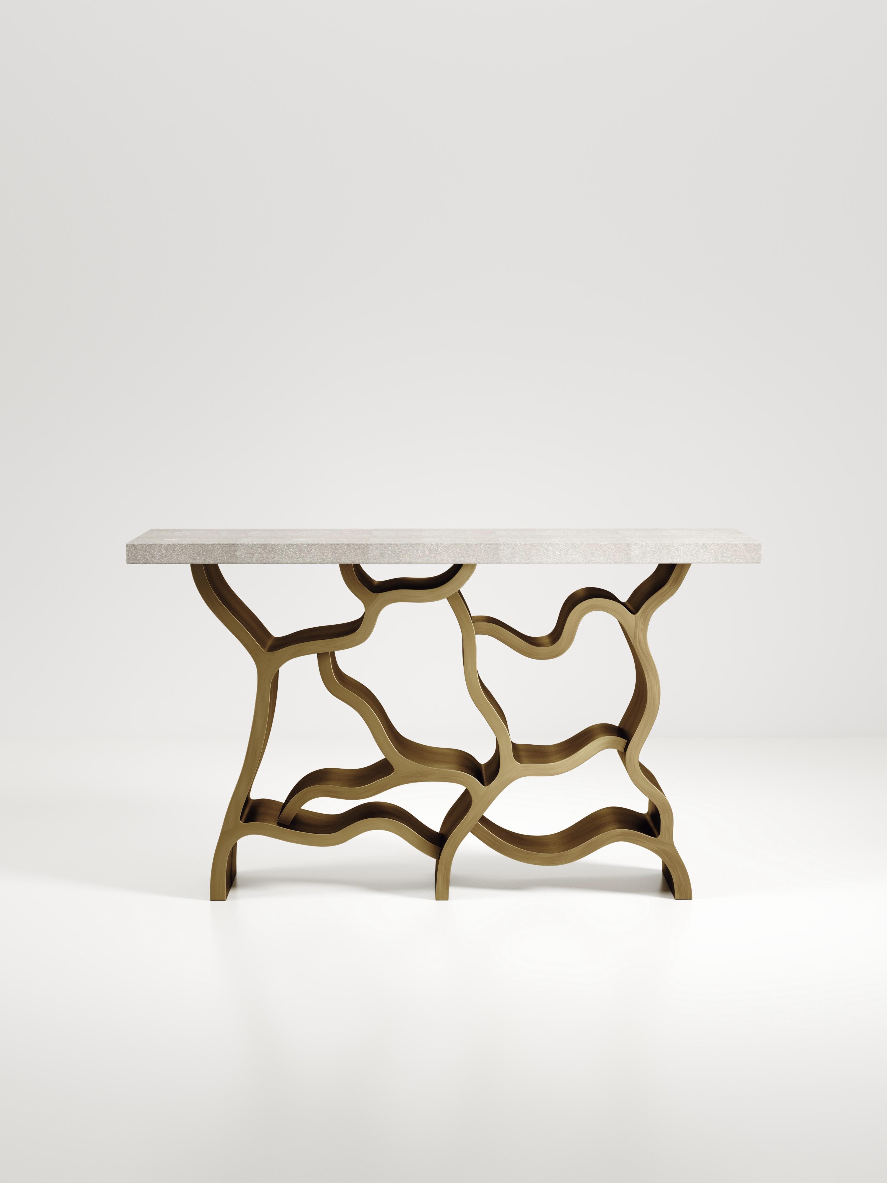 The Leaf Console Table by Kifu Paris is a dramatic and organic piece. The cream shagreen inlaid rectangle top sits on a striking bronze-patina brass base that emulates intertwining branches. This piece is designed by Kifu Augousti the daughter of