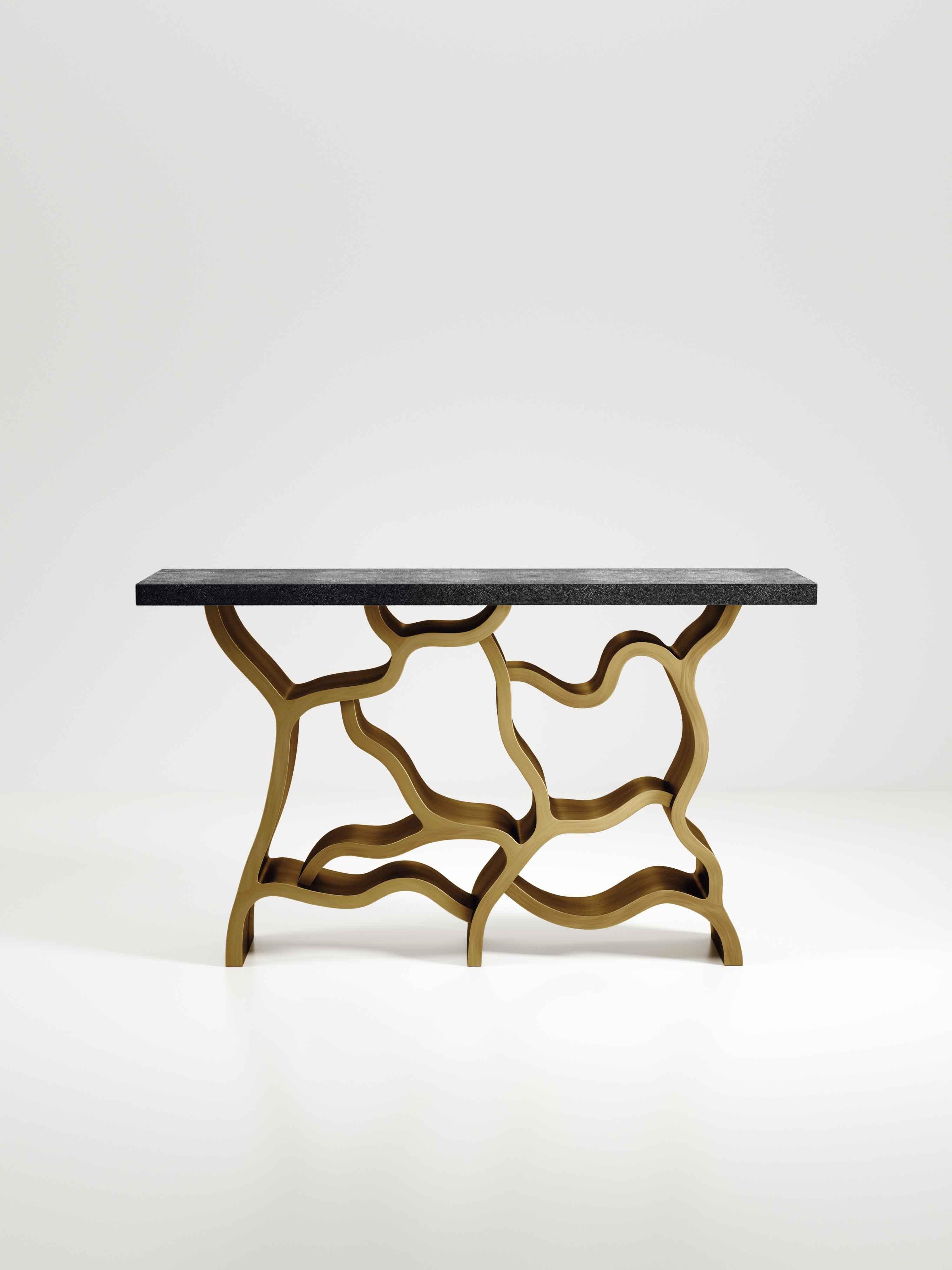 La table console Leaf de Kifu Paris est une pièce spectaculaire et organique. Le plateau rectangulaire incrusté de galuchat noir de charbon repose sur un socle en laiton bronze-patine qui évoque des branches entrelacées. Cette pièce a été conçue par