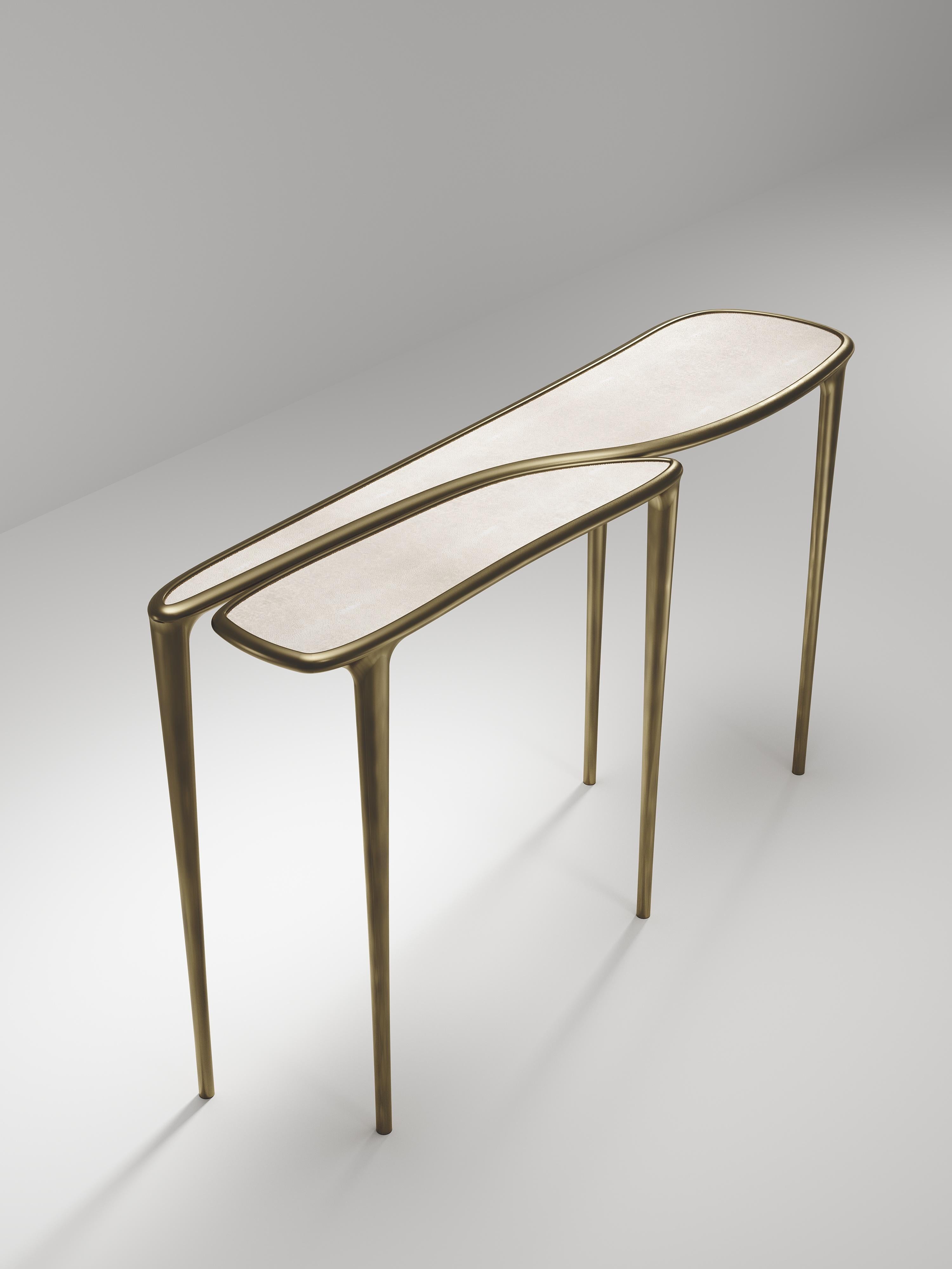 The Frequency console table by R & Y Augousti is sleek piece with a vintage-modern feel. The piece explores fluid organic lines with subtle detailing to create the signature Augousti aesthetic. The piece is inlaid in a mixture of cream shagreen and