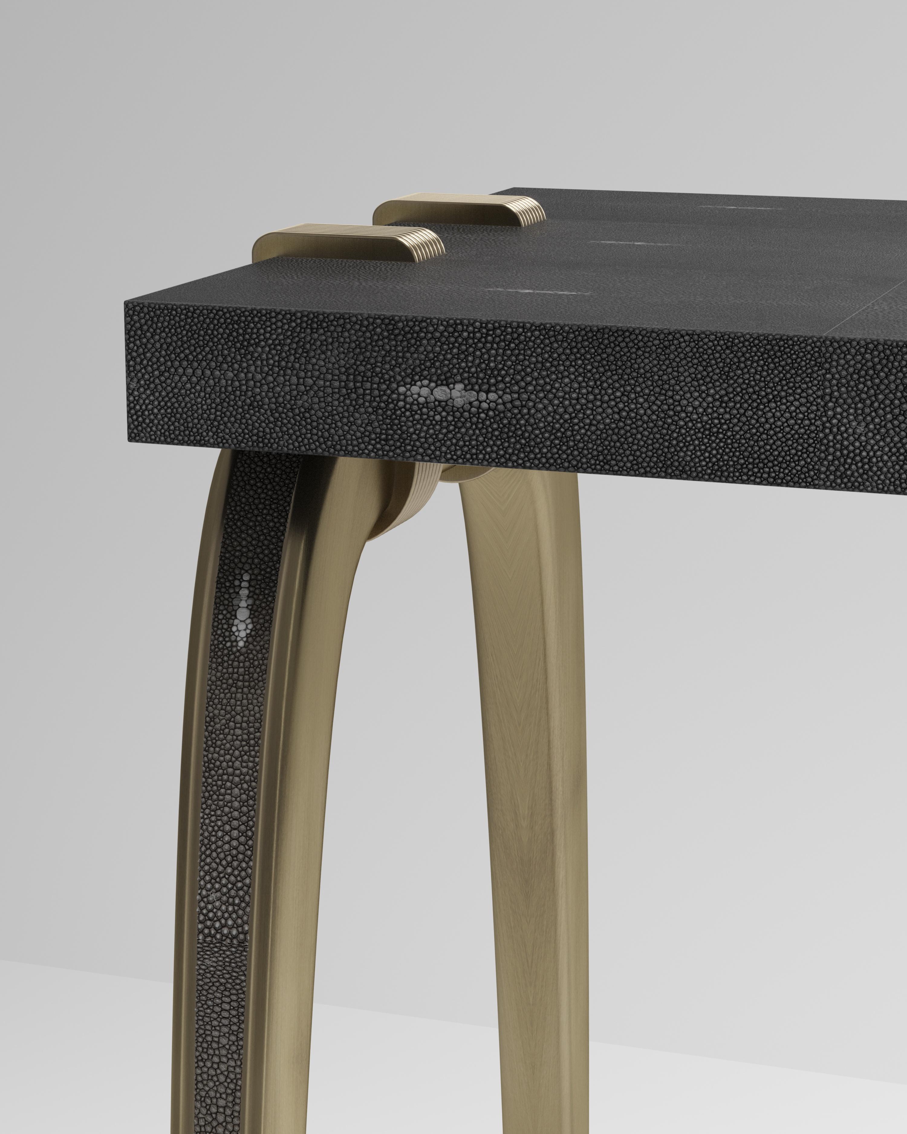 La table console Sonia est un modèle emblématique d'Augousti, qui met en valeur le savoir-faire exquis de la marque. Les pieds incrustés de galuchat s'accrochent sur le côté du plateau rectangulaire en galuchat noir. Cette pièce est un clin d'œil à