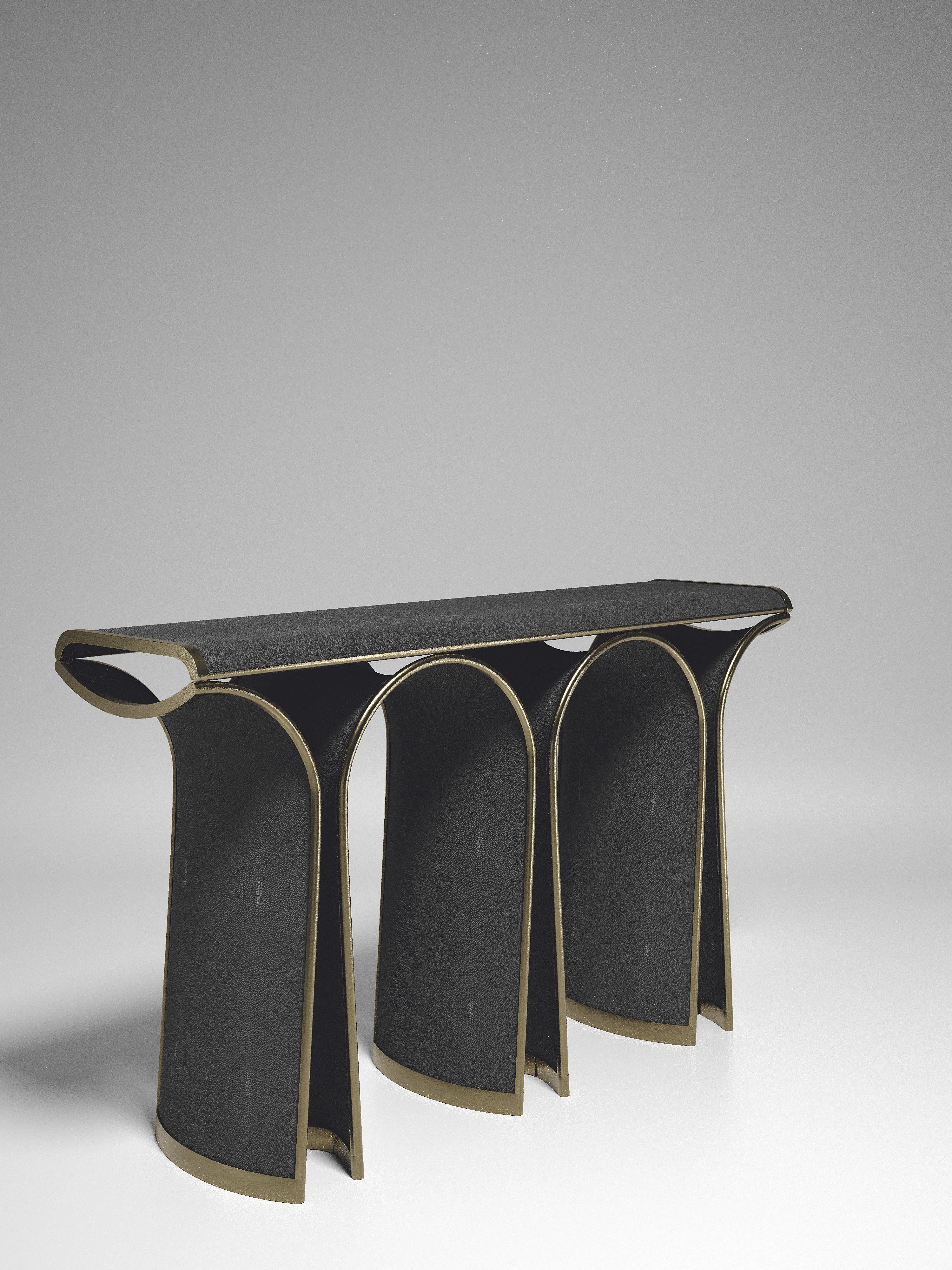 La console Nymphea de R&Y Augousti en galuchat noir avec des détails en laiton bronze-patine explore l'ADN emblématique de la marque, qui consiste à intégrer l'artisanat d'antan dans une ambiance contemporaine et tout à fait luxueuse. Disponible