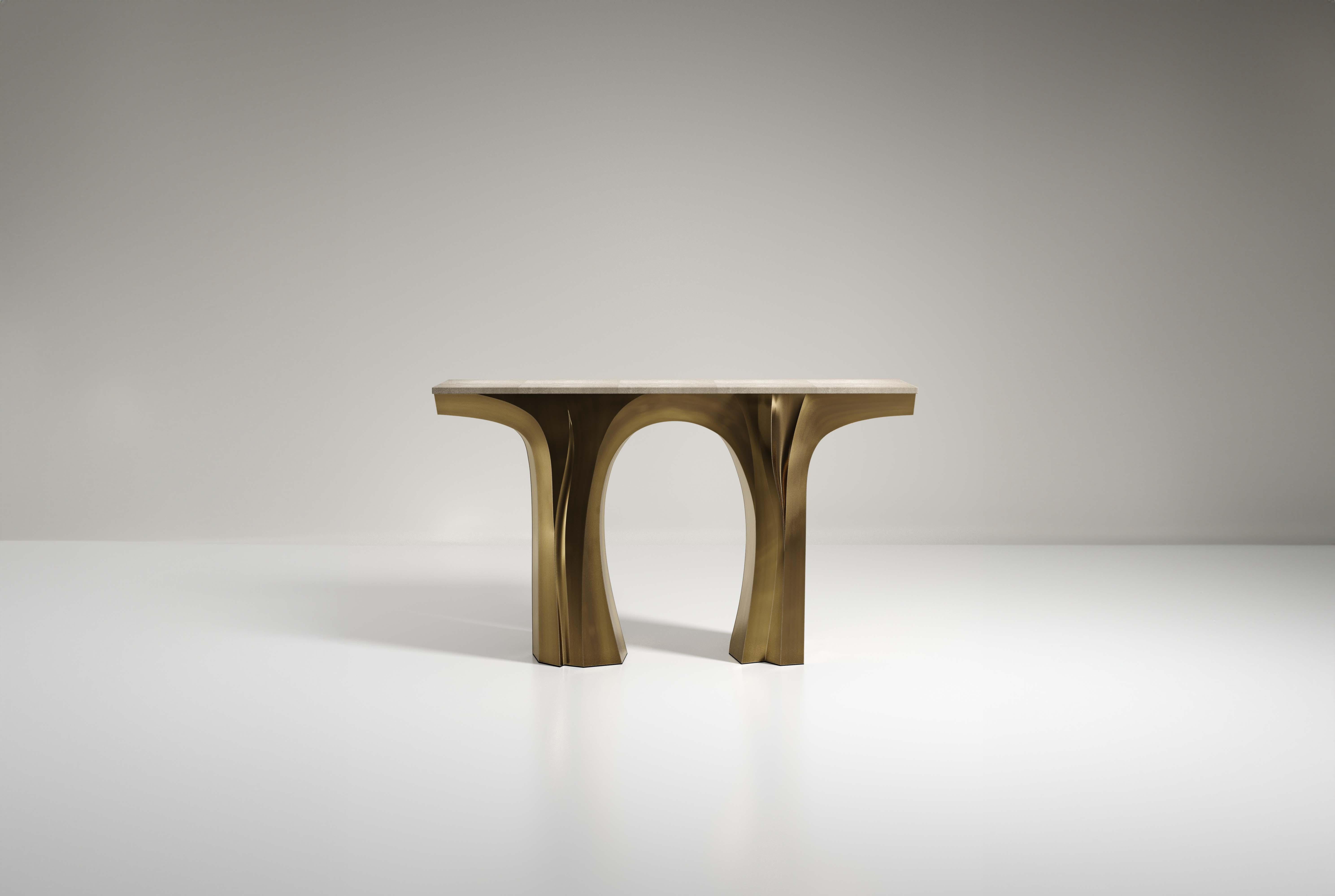 The Alma console by R&Y Augousti is a sculptural and versatile piece. The cream shagreen inlaid top morphs into dramatic hand-carved bronze-patina brass legs. The grooves and details on the base allow the console to have different expressions from