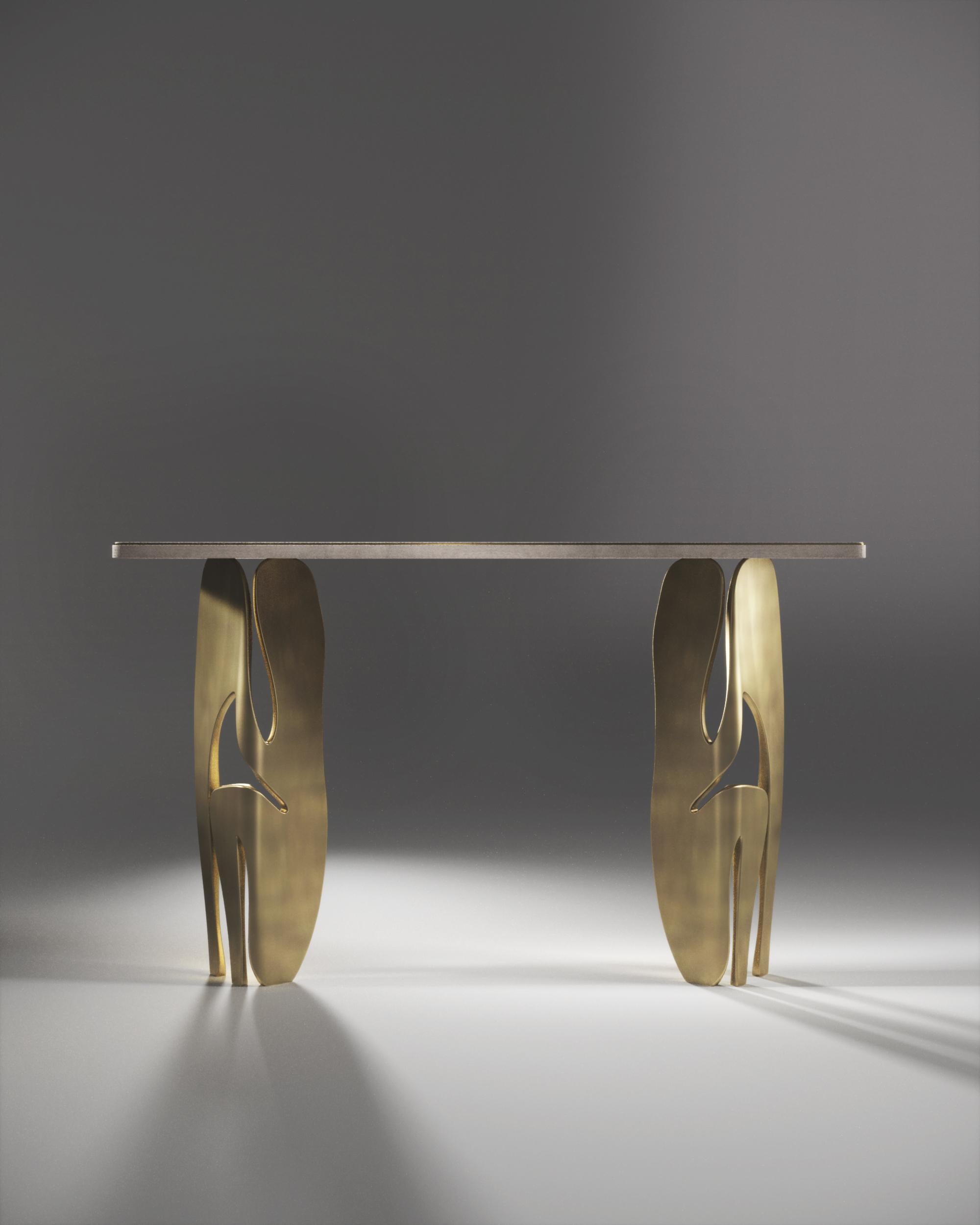 La console Metropolis II de R&Y Augousti est une pièce maîtresse. Le plateau incrusté de galuchat crème repose sur une paire de pieds sculpturaux spectaculaires en laiton bronze-patina, mettant en valeur l'incroyable travail artisanal de la marque.