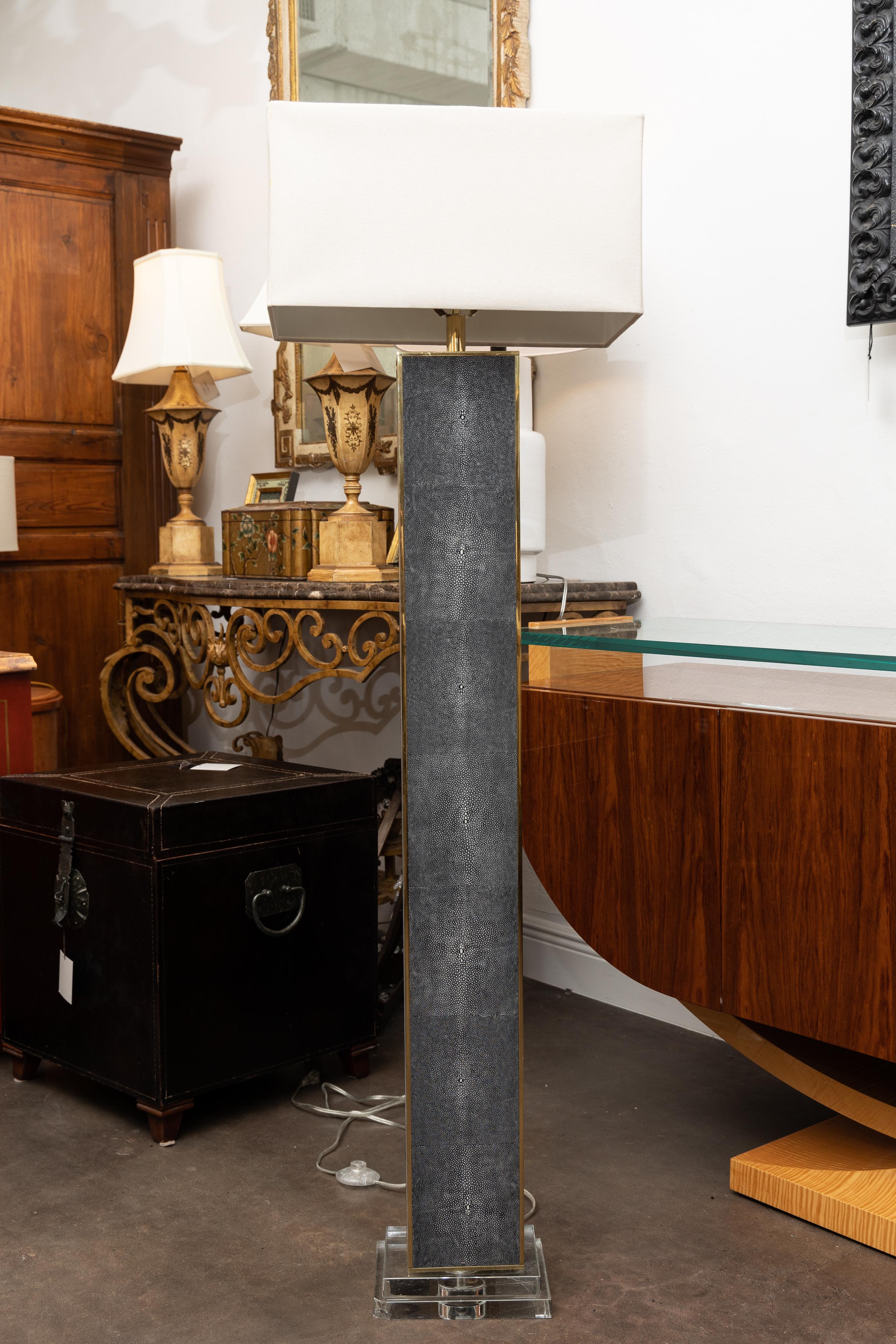 This is a Shagreen-clad floor lamp, rectangular in shape, framed by brass edging and situated on a double tier lucite base, possibly R&Y Agousti.o.