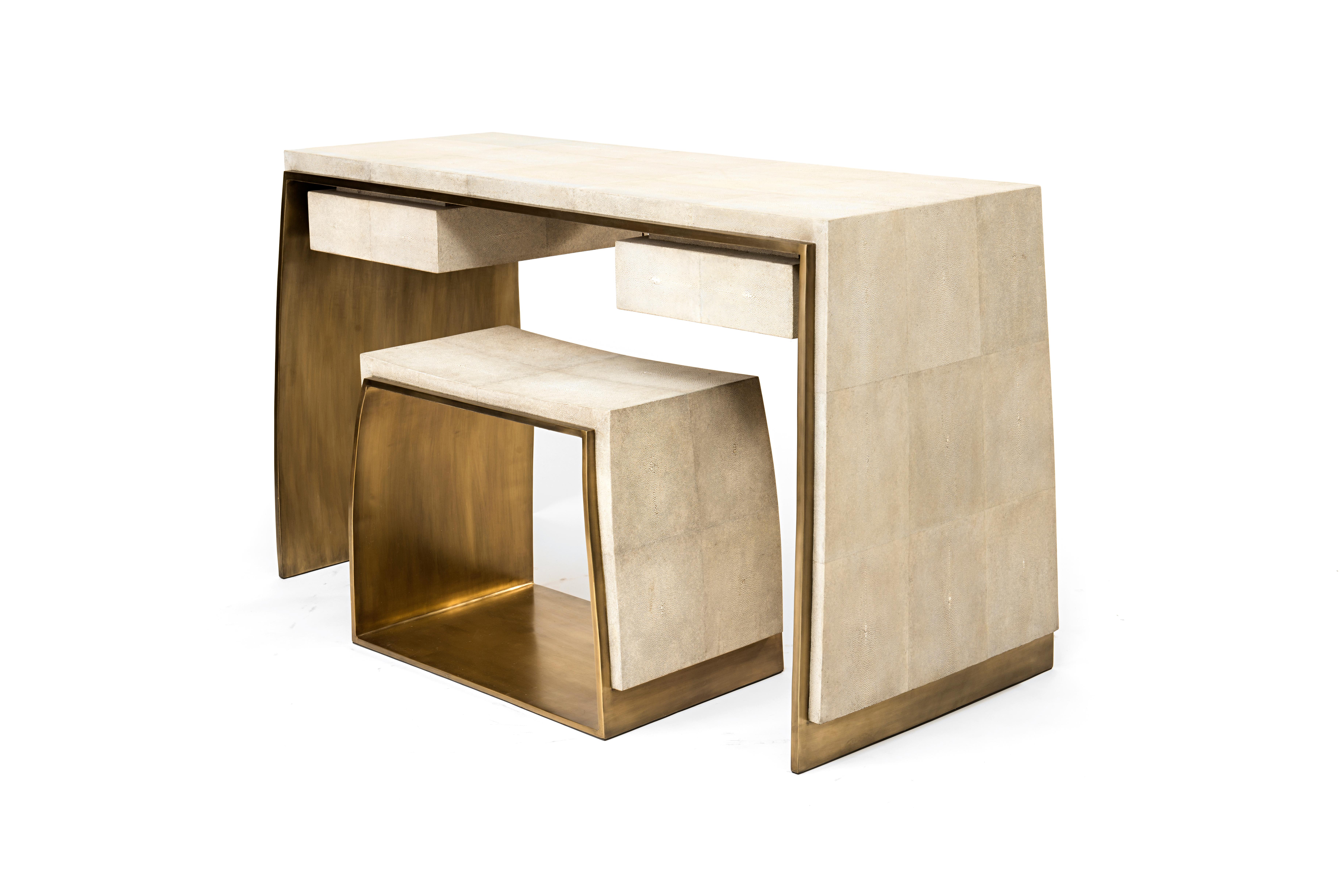 The Laurens Writing Desk and matching Stool are both graphic and minimalist with their asymmetry overlay of cream shagreen sitting on top of a bronze-patina brass structure. The desk includes 2 drawers. Pieces can be sold separately. A console