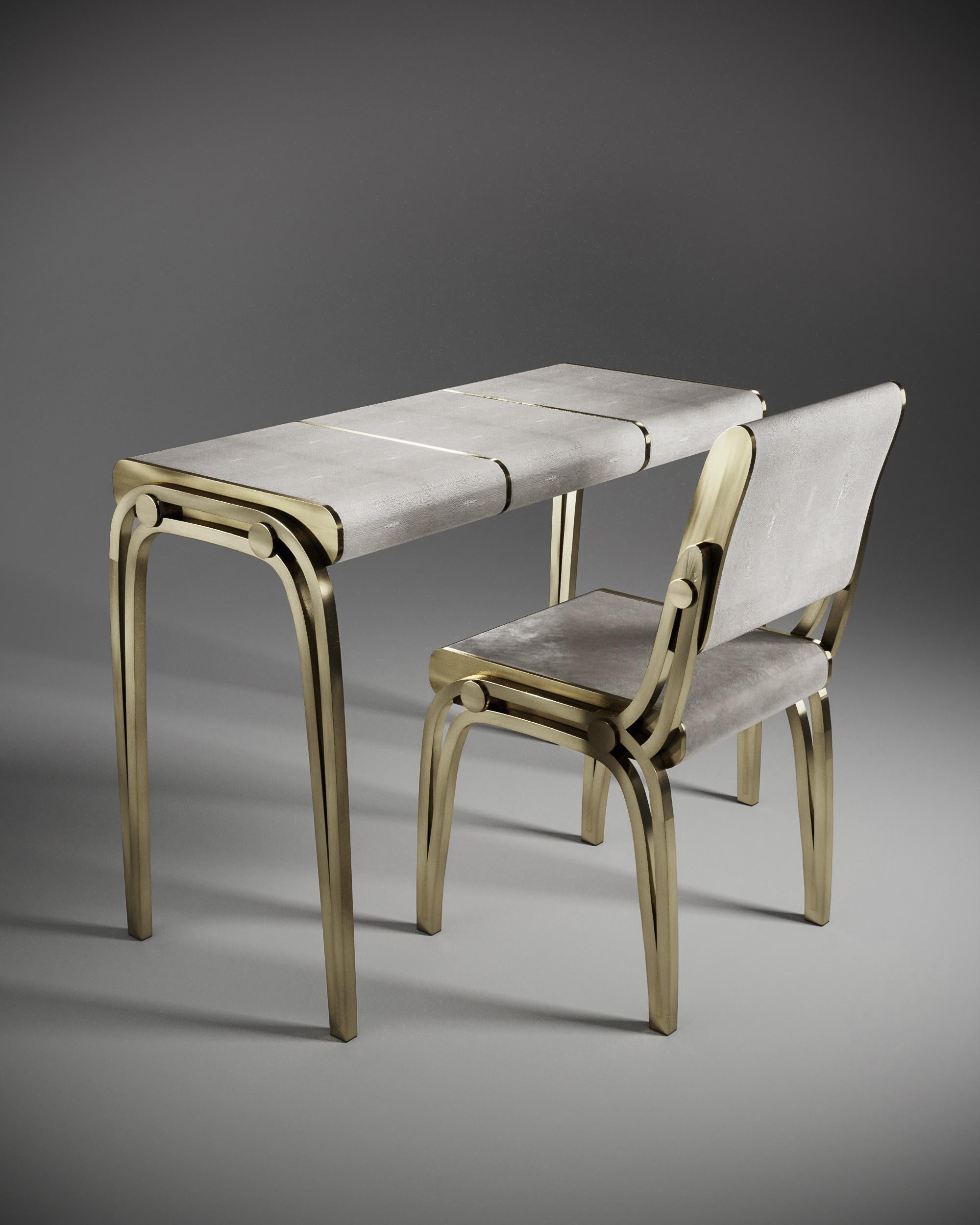 Der Schreibtisch Victoria mit cremefarbener Chagrineinlage von R&Y Augousti ist ein raffiniertes, minimalistisches Möbelstück, das mit seinen verschlungenen Messingdetails eine elegante und luxuriöse Ästhetik schafft. Die drei abgerundeten