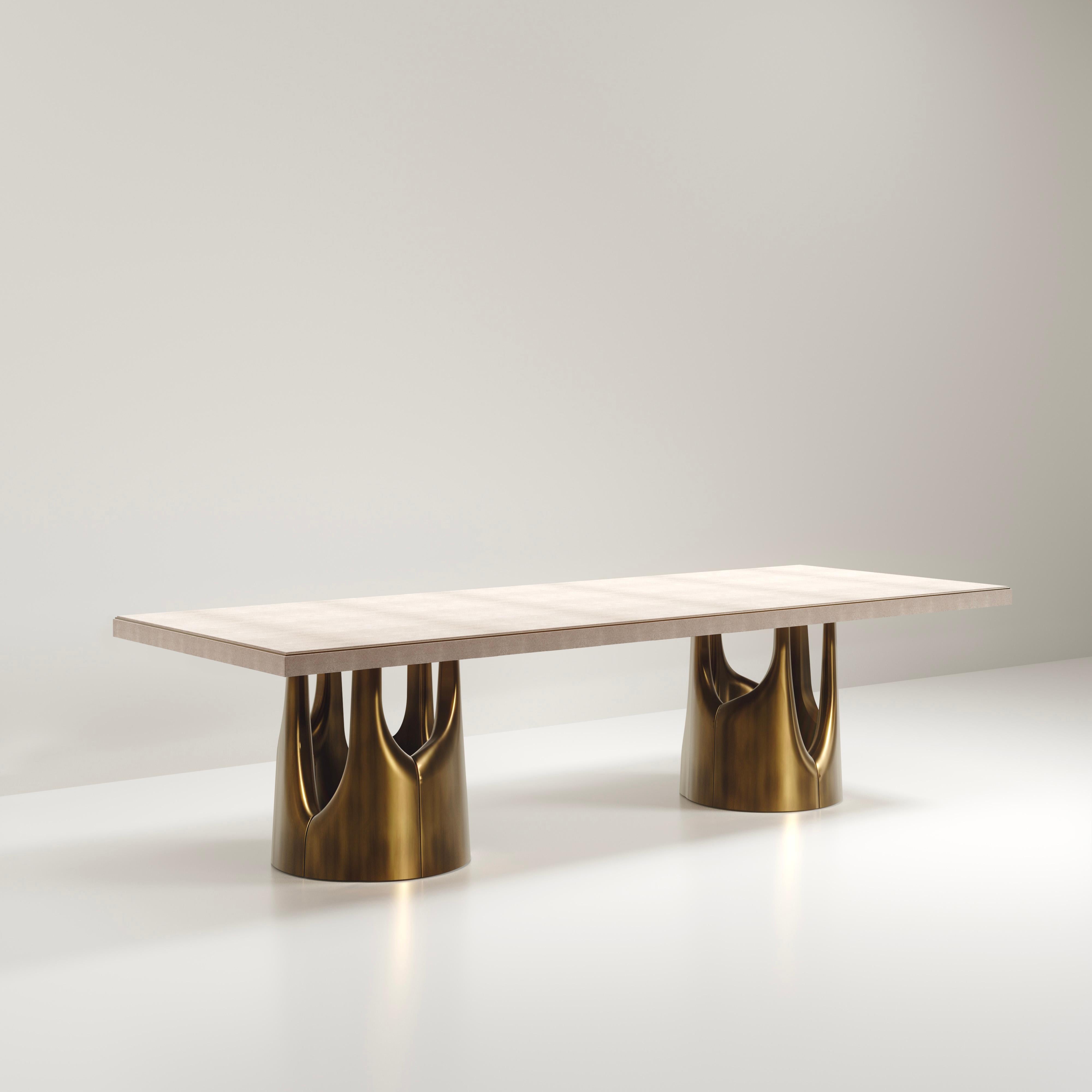 The Triptych I dining table by R&Y Augousti is a stunning multi-faceted sculptural piece. The beautiful hand craved details on the bronze-patina base demonstrate the incredible artisan work of Augousti. The top is inlaid in cream shagreen. Available
