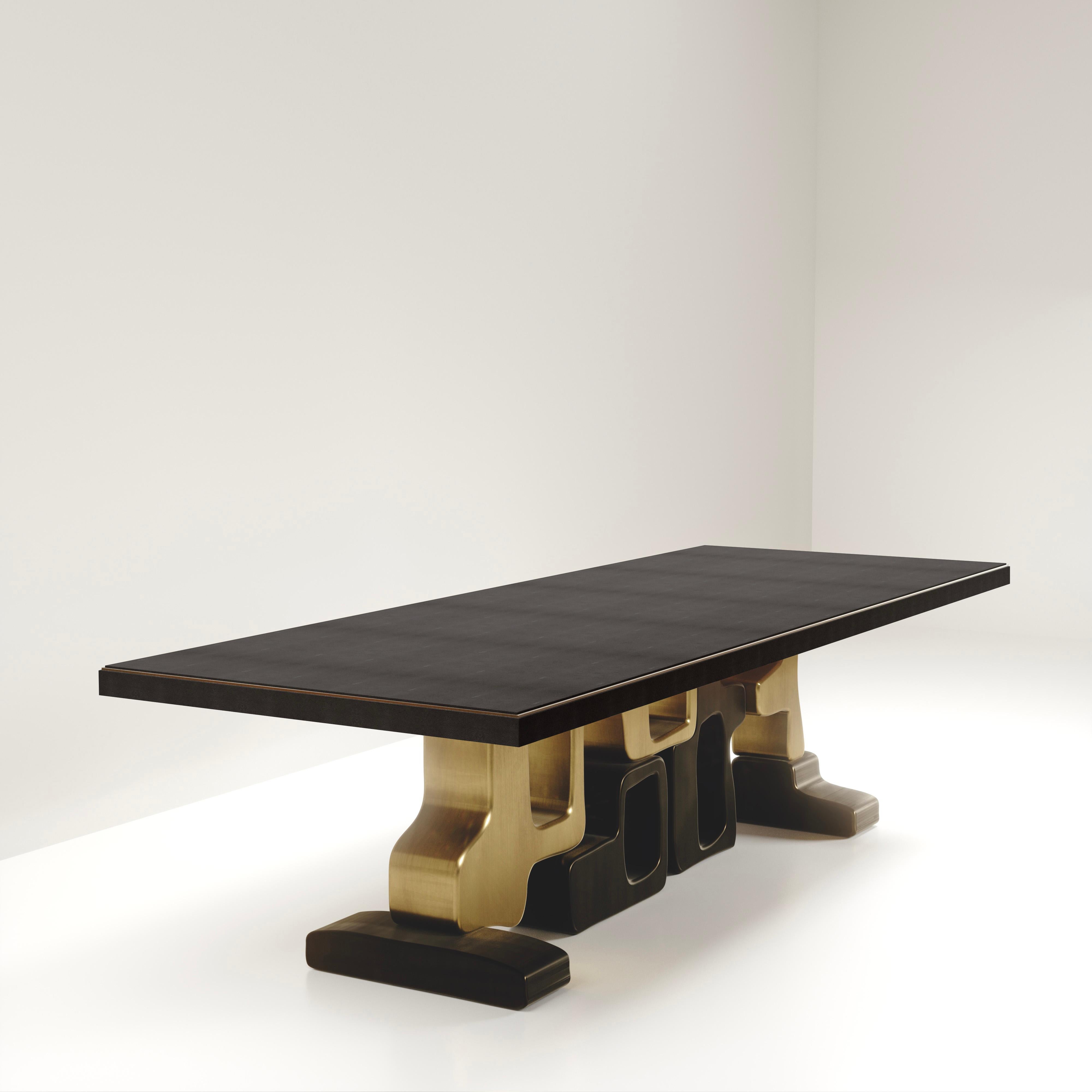 The Apoli II dining table by Kifu Paris is both dramatic and organic its unique design. The black shagreen inlaid top sits on a long clustered geometric and sculptural bronze-patina brass base. This piece is designed by Kifu Augousti the daughter of