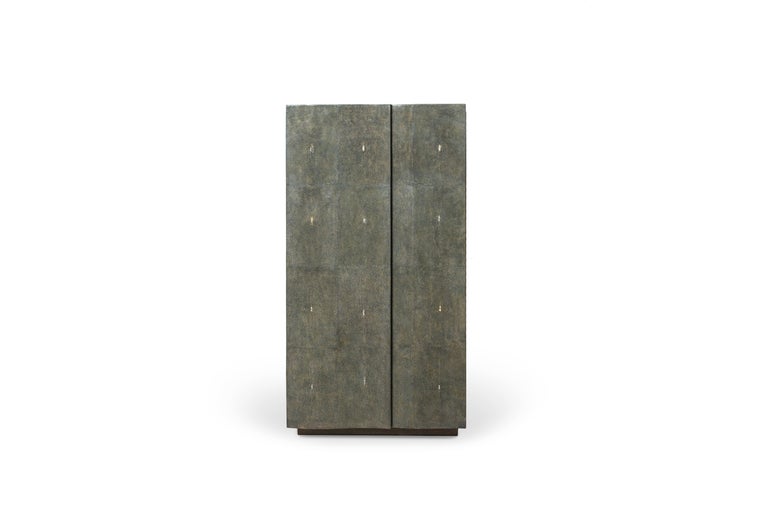 This jewelry cabinet in antique black shagreen is the ultimate luxury storage unit for any living space. The doors overlap over one another to create subtle geometry within the overall structure of the piece. The inside of the cabinet is inlaid in