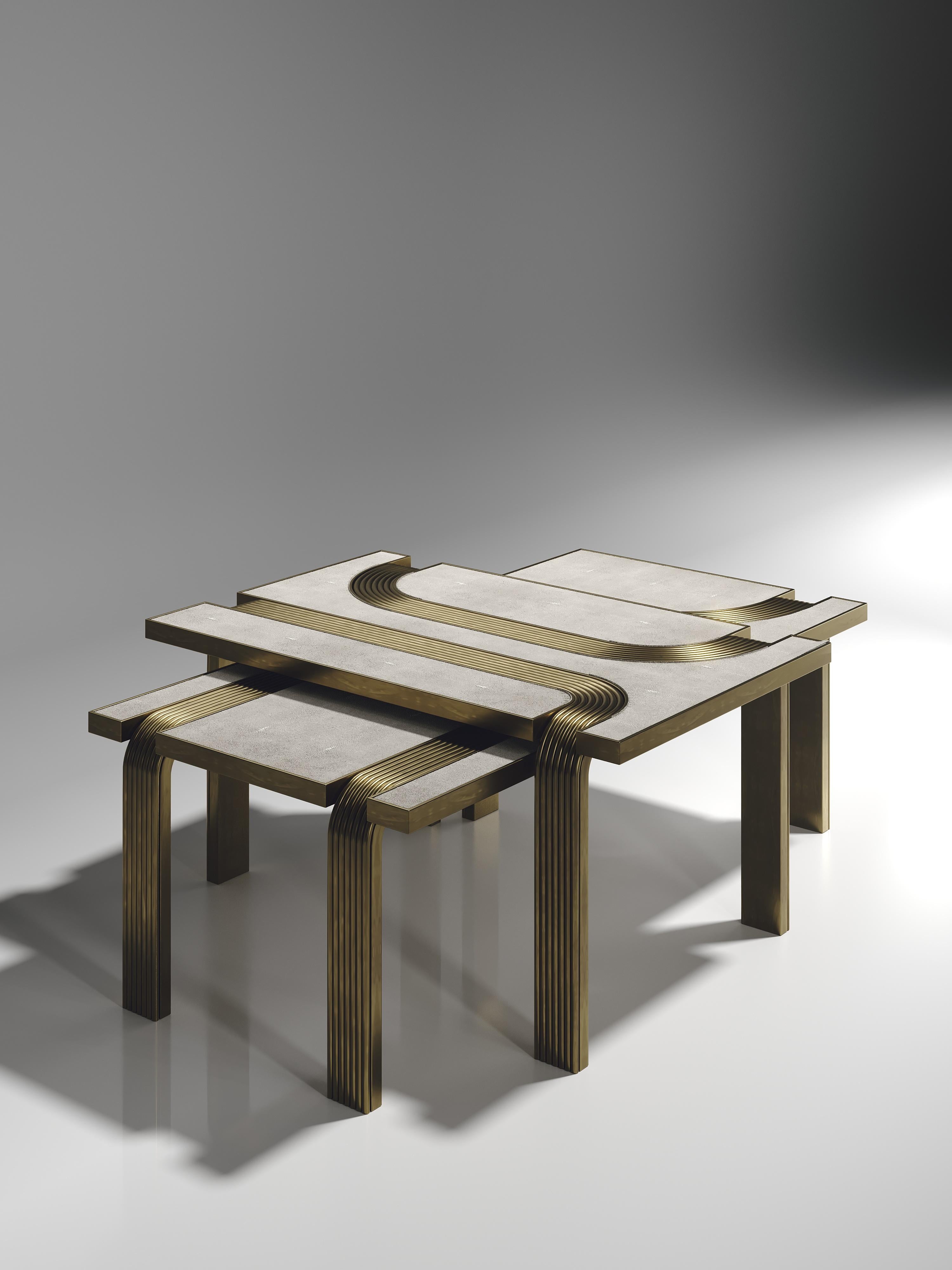 Le set de 2 tables basses gigognes Licol de R&Y Augousti en galuchat crème avec des détails en laiton bronze-patine explore l'ADN emblématique de la marque en apportant l'artisanat d'antan dans une ambiance contemporaine et tout à fait luxueuse. Ces