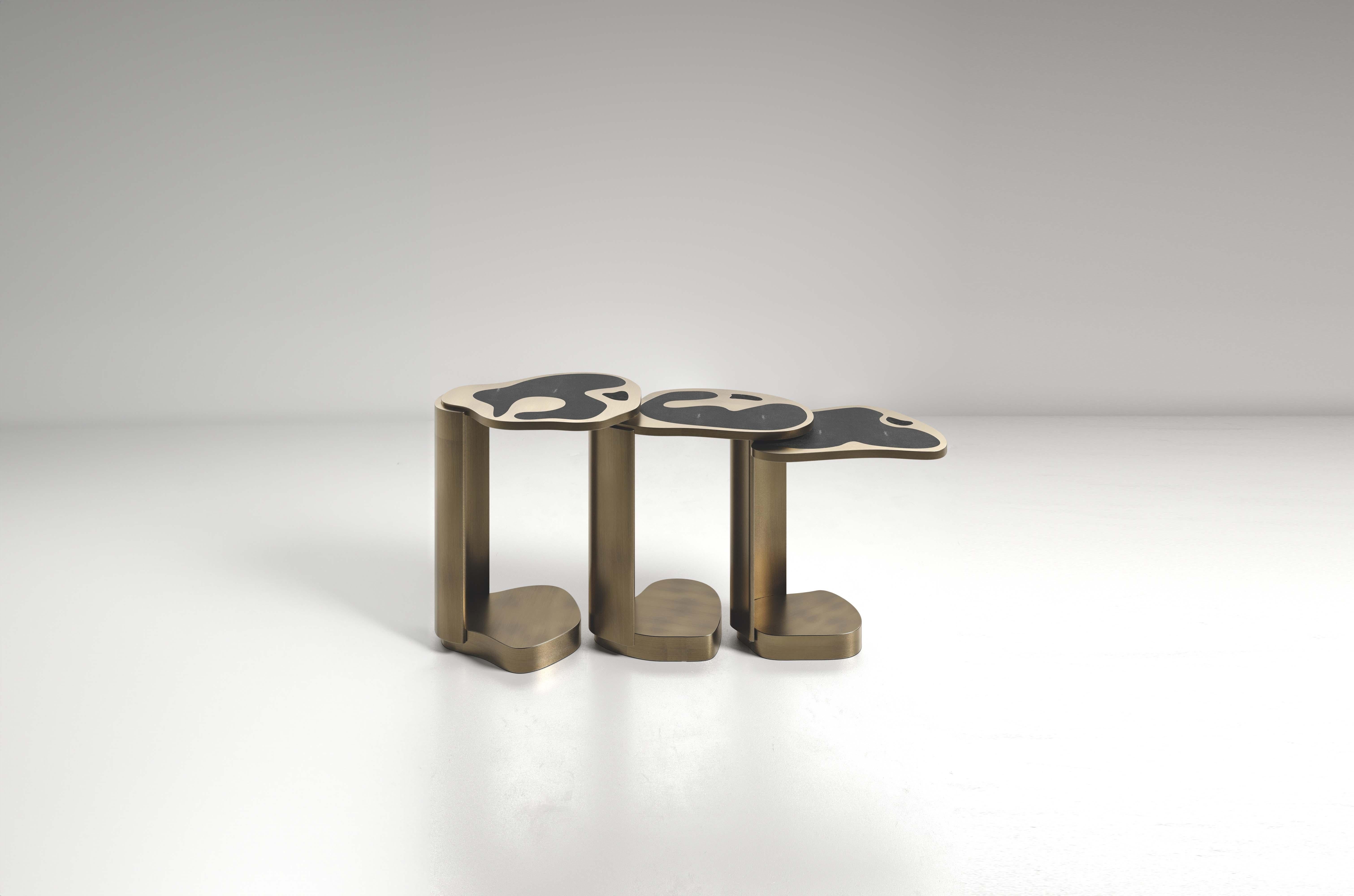 The Mask Nesting Side Tables by Kifu Paris are versatile and organic pieces. The amorphous tops and bases are inlaid in a mixture of coal black shagreen, black pen shell and bronze-patina brass. This piece is designed by Kifu Augousti the daughter
