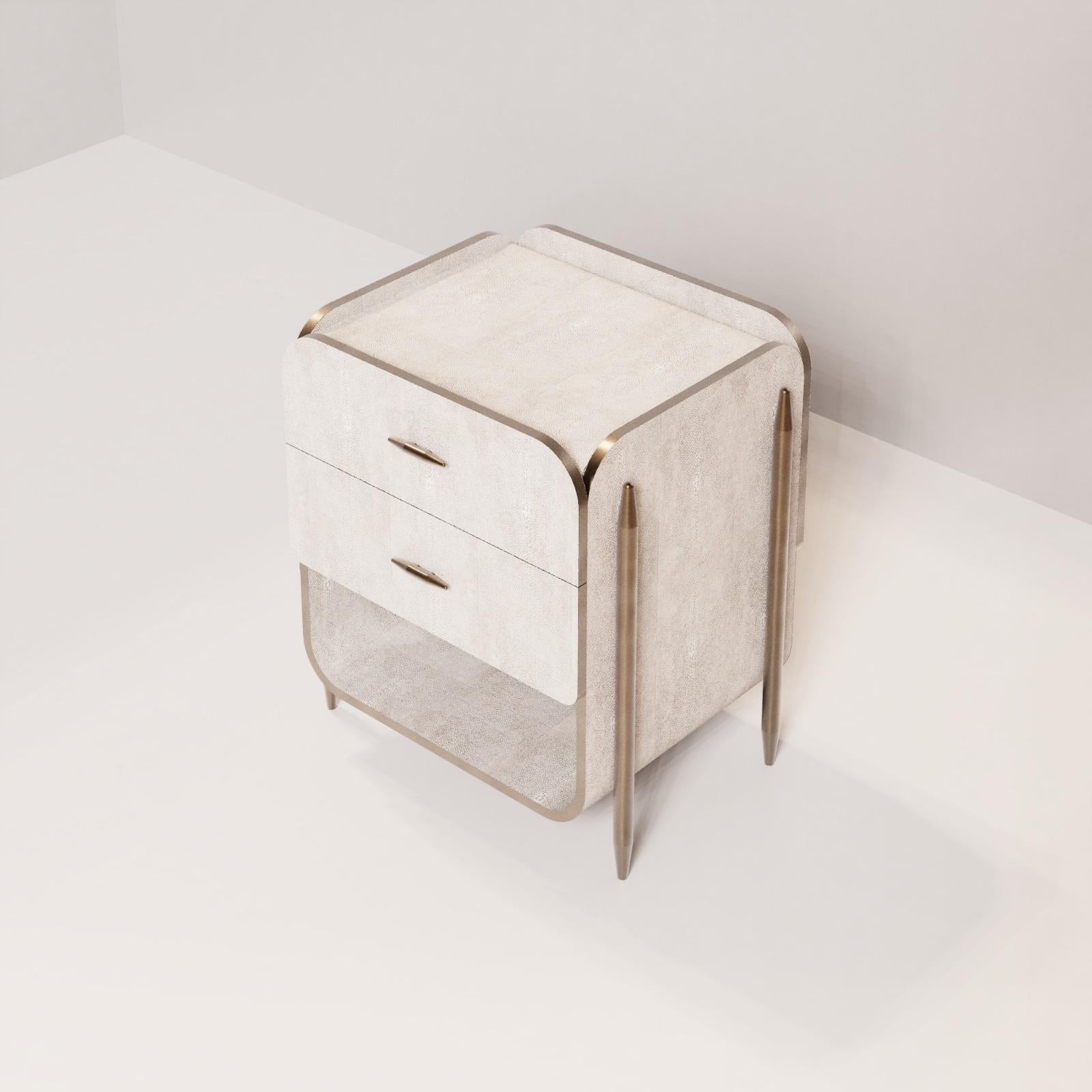 The Dandy Square Bedside Table by Kifu Paris is an elegant and a luxurious home accent, inlaid in cream shagreen with bronze-patina brass details. This piece includes 2 drawers total and an open shelf inlaid in shagreen. Available zith 2 drawers and