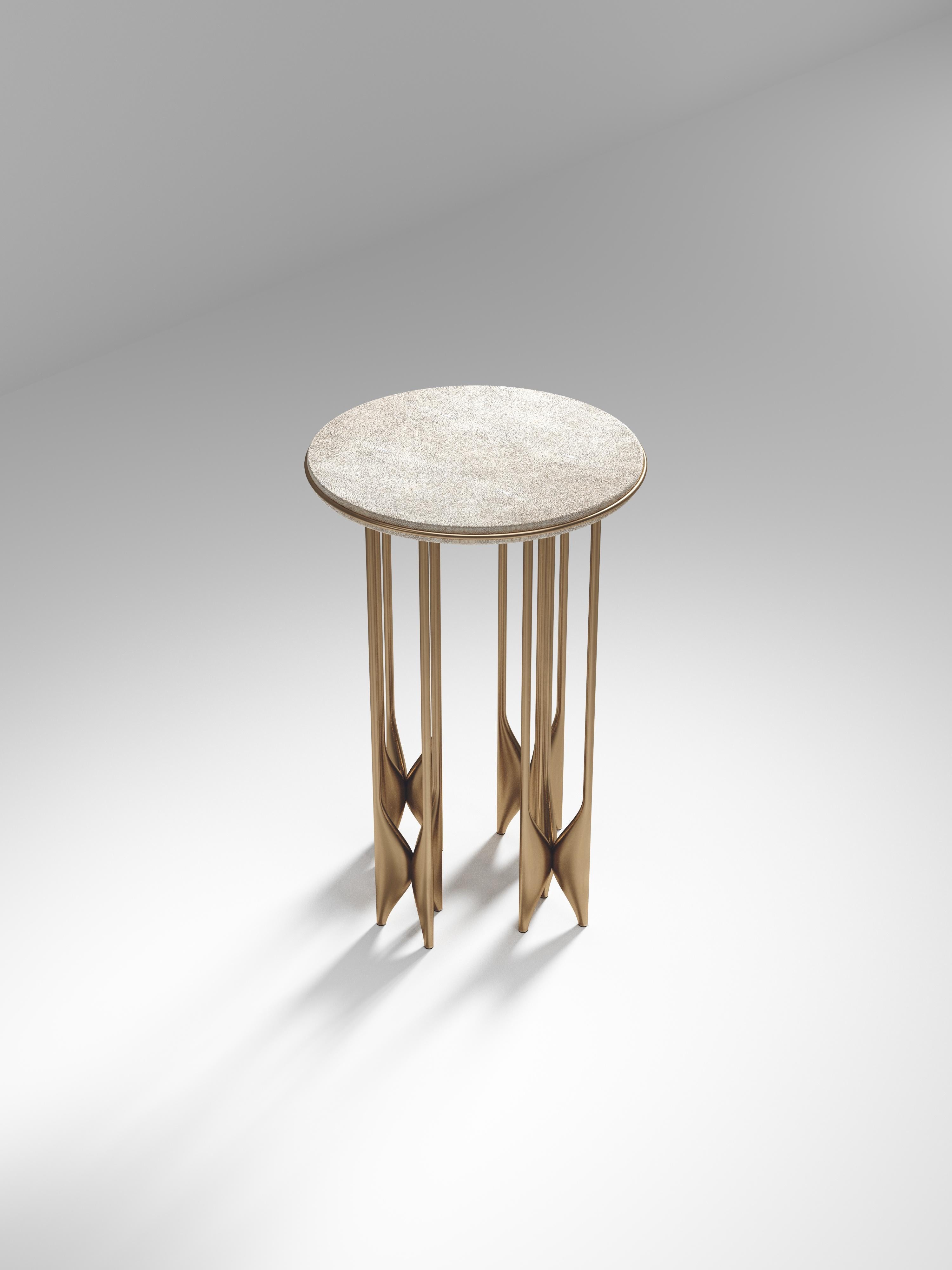 The Plumeria Side Table by Kifu Paris is a dramatic and sculptural piece. The cream shagreen inlaid top sits on clusters of bronze-patina brass legs that are conceptually inspired by bird feathers floating on top of a lake. The border of the top is