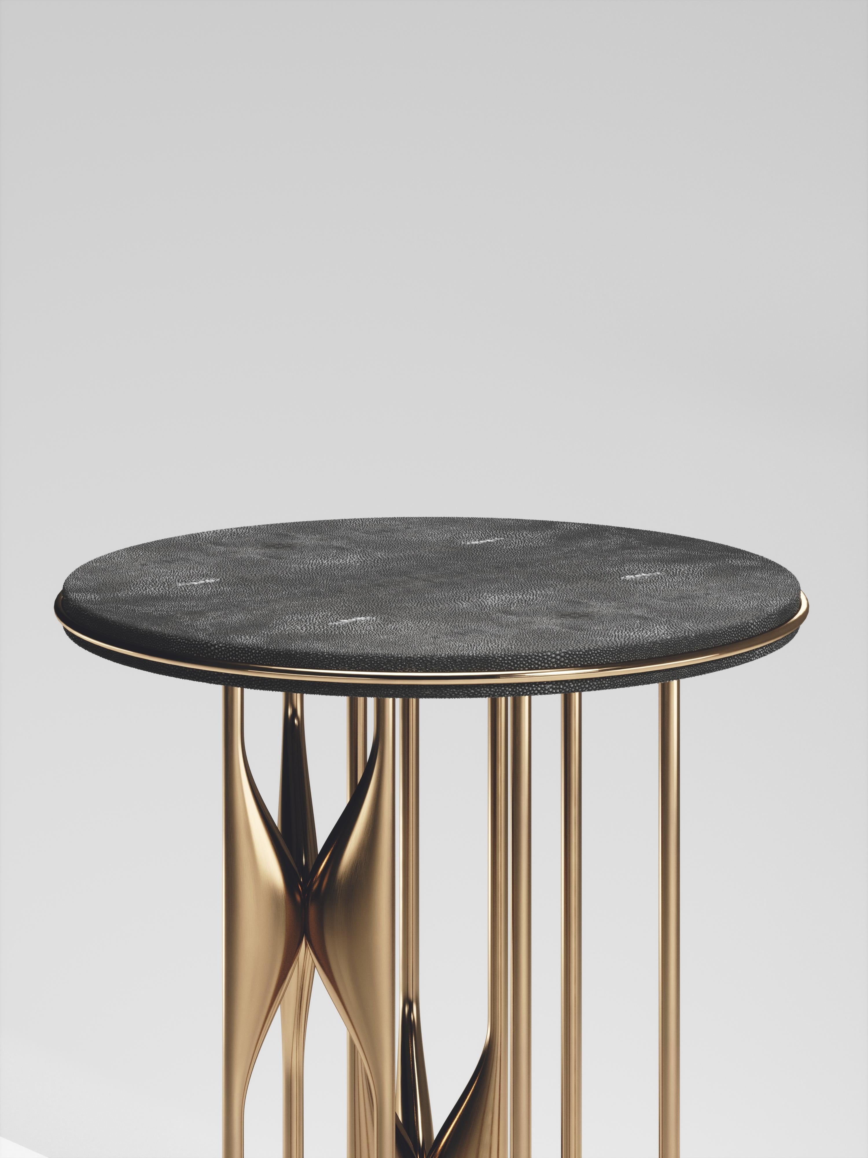 The Plumeria side table by Kifu Paris is a dramatic and sculptural piece. The coal black shagreen inlaid top sits on clusters of bronze-patina brass legs that are conceptually inspired by bird feathers floating on top of a lake. The border of the