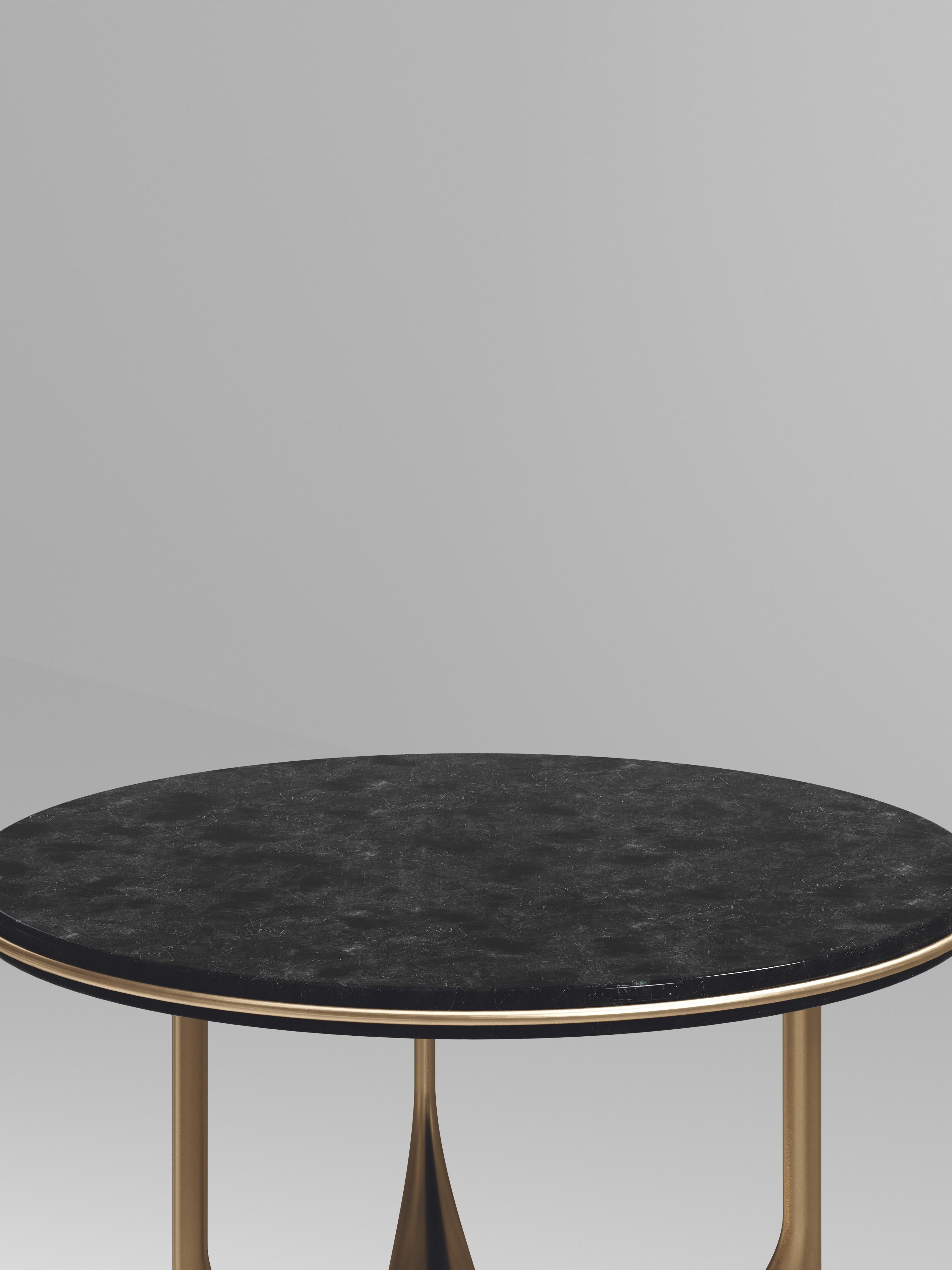 The Plumeria side table II by Kifu Paris is a dramatic and sculptural piece. The black shell inlaid top sits on a sculptural bronze-patina brass base that is conceptually inspired by bird feathers floating on top of a lake. The border of the top is