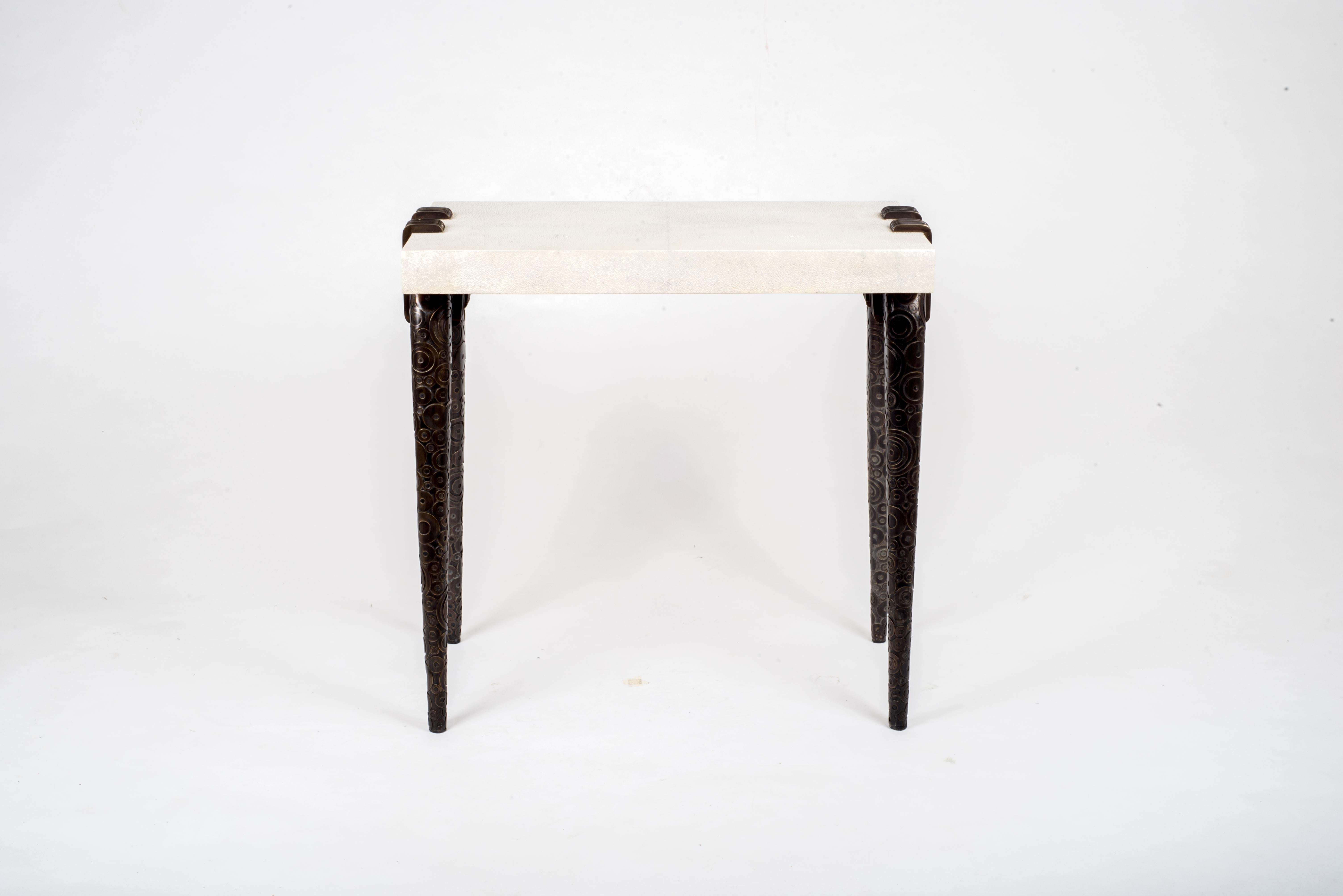The circular dark bronze patina brass inlay details on the legs of the Vogue side table shows the true craftsmanship of Augousti artisans. The legs clasp onto the side of the cream shagreen rectangle top. This piece is a nod to the Art-Deco period