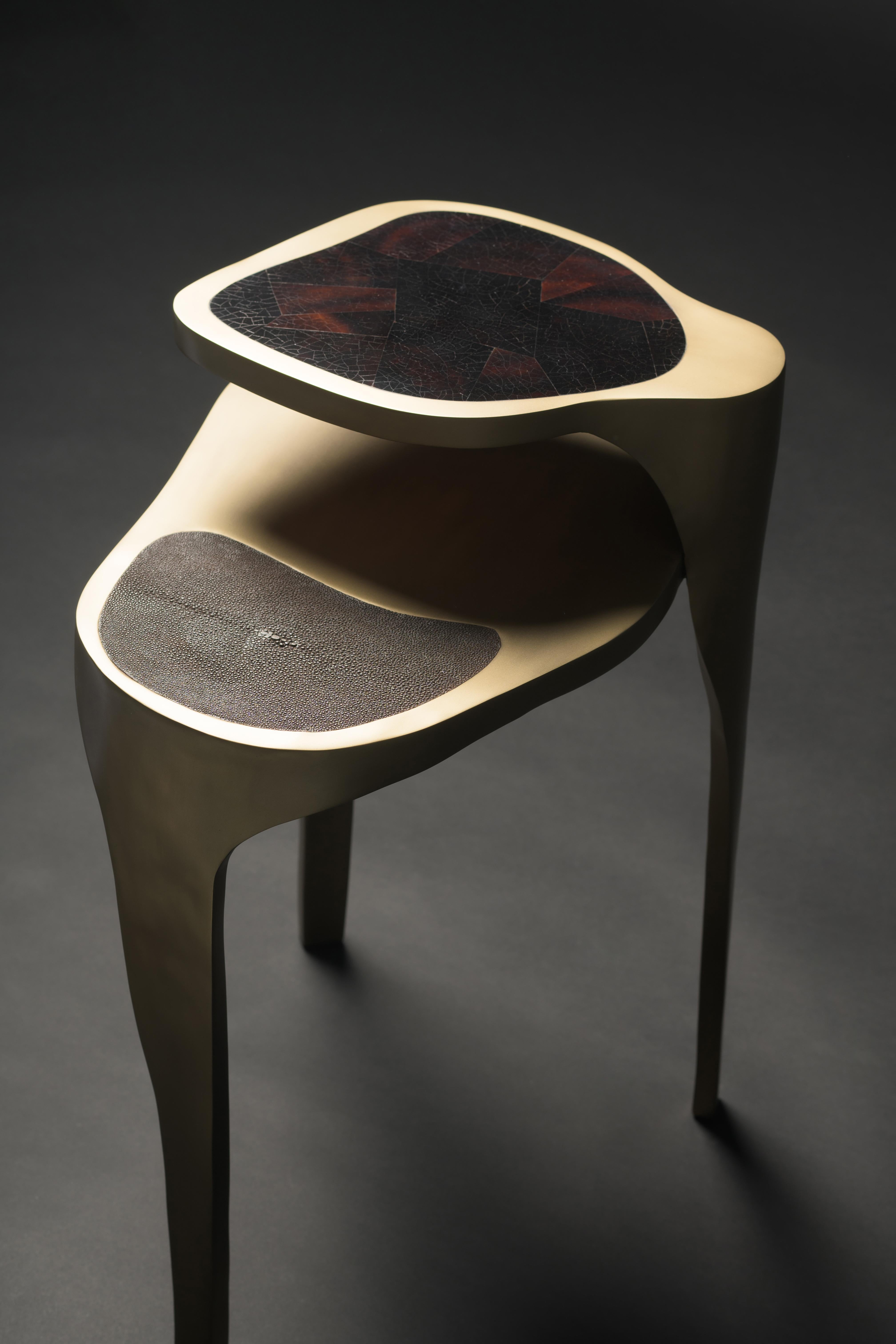 The Ginko Sde table by R & Y Augousti is an elegant and versatile piece. The piece is both sculptural and graphic with its organic shape and floating two top detail. The piece is inlaid in a mixture of mink shagreen, brown pen shell and bronze