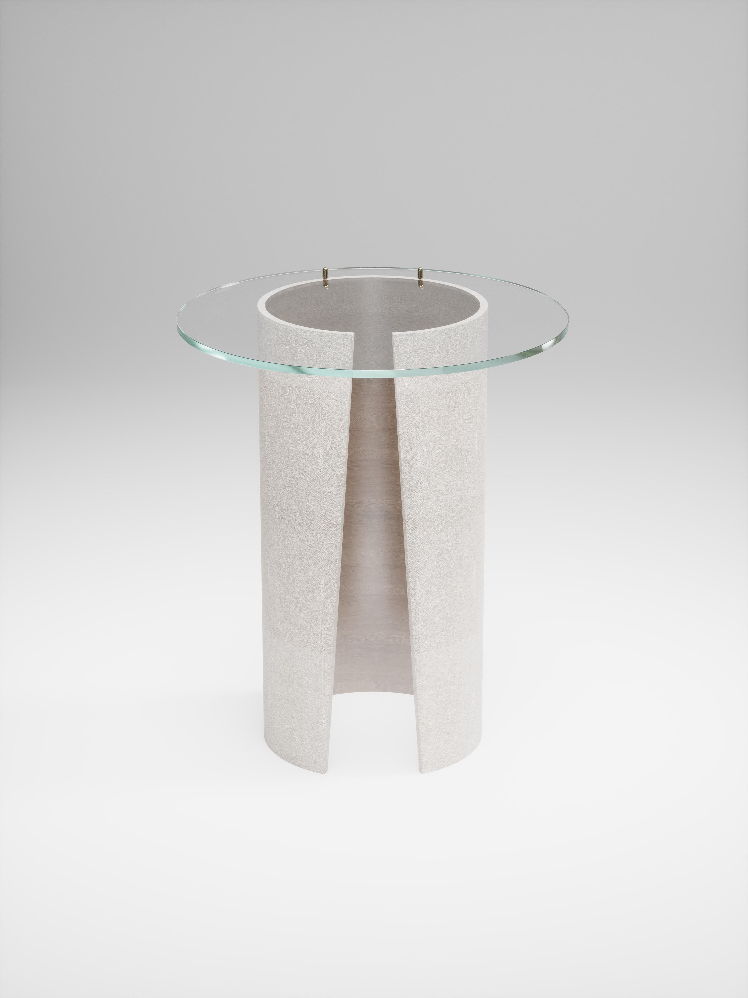 La table d'appoint Wrap de R&Y Augousti incrustée de galuchat crème avec un plateau en verre est une pièce élégante et classique pour votre maison. Le plateau rond en verre repose sur la base asymétrique incrustée de galuchat crème et est fixé par