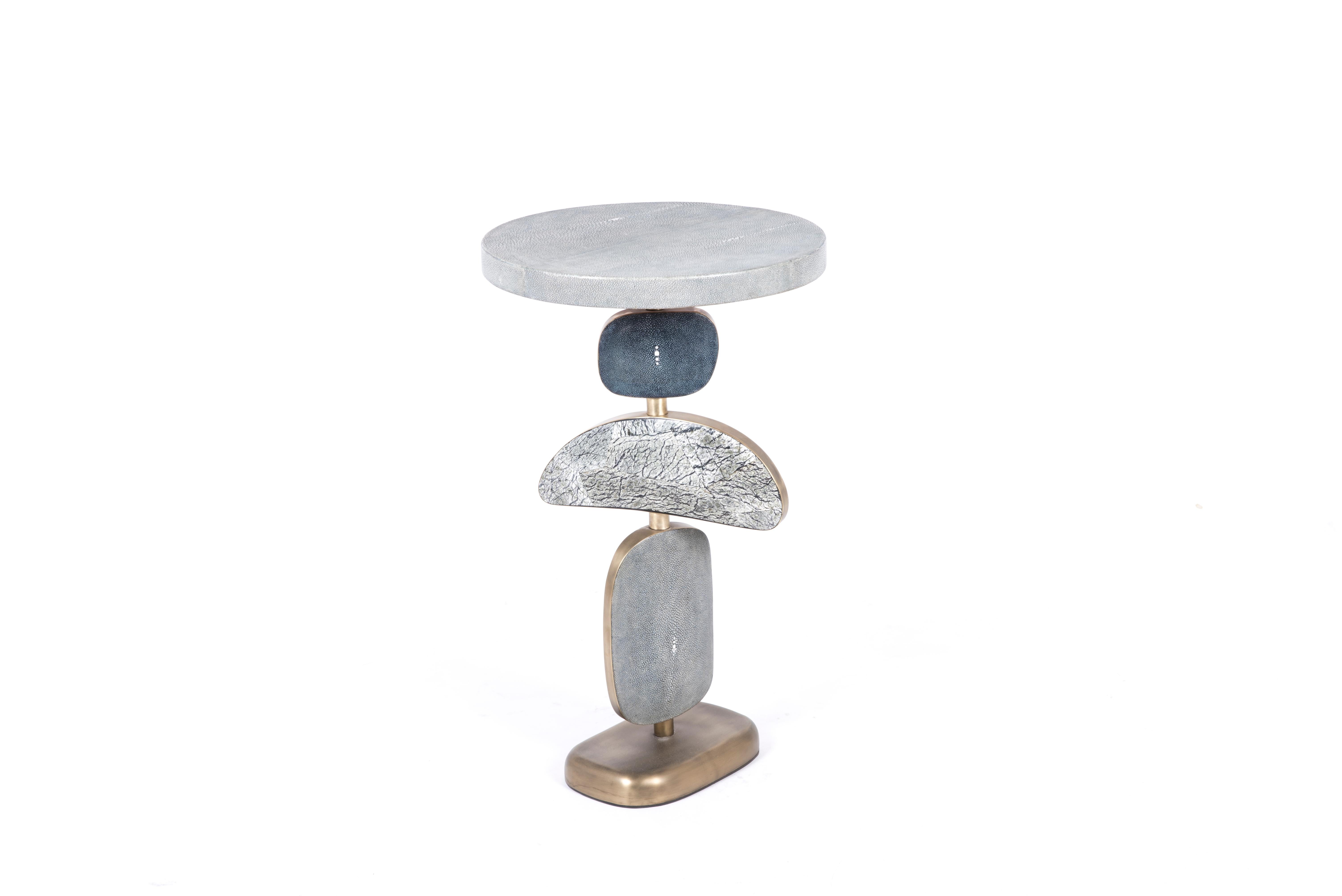 The cosmo side table by Kifu Paris is a whimsical and sculptural piece, inlaid in different shades of blue Shagreen, Baguio stone and bronze-patina brass. The amorphous shapes on the bottom part can be moved to adjust the angle of each part.