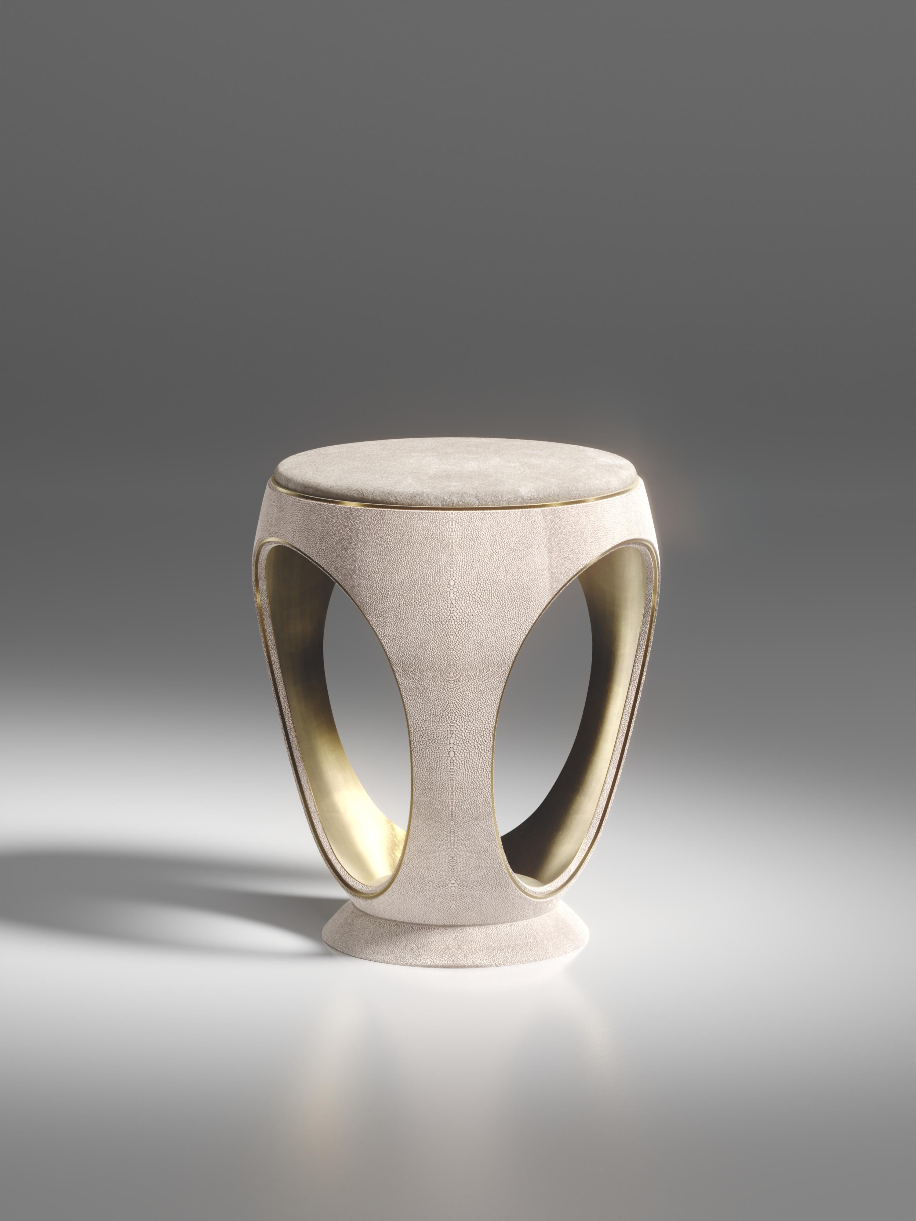 Le tabouret annulaire en galuchat crème est l'une des pièces les plus emblématiques de la Collection R&Y Augousti. De forme sculpturale, semblable à un bijou, cette pièce a été relookée avec un discret détail d'indentation en laiton patiné bronze à
