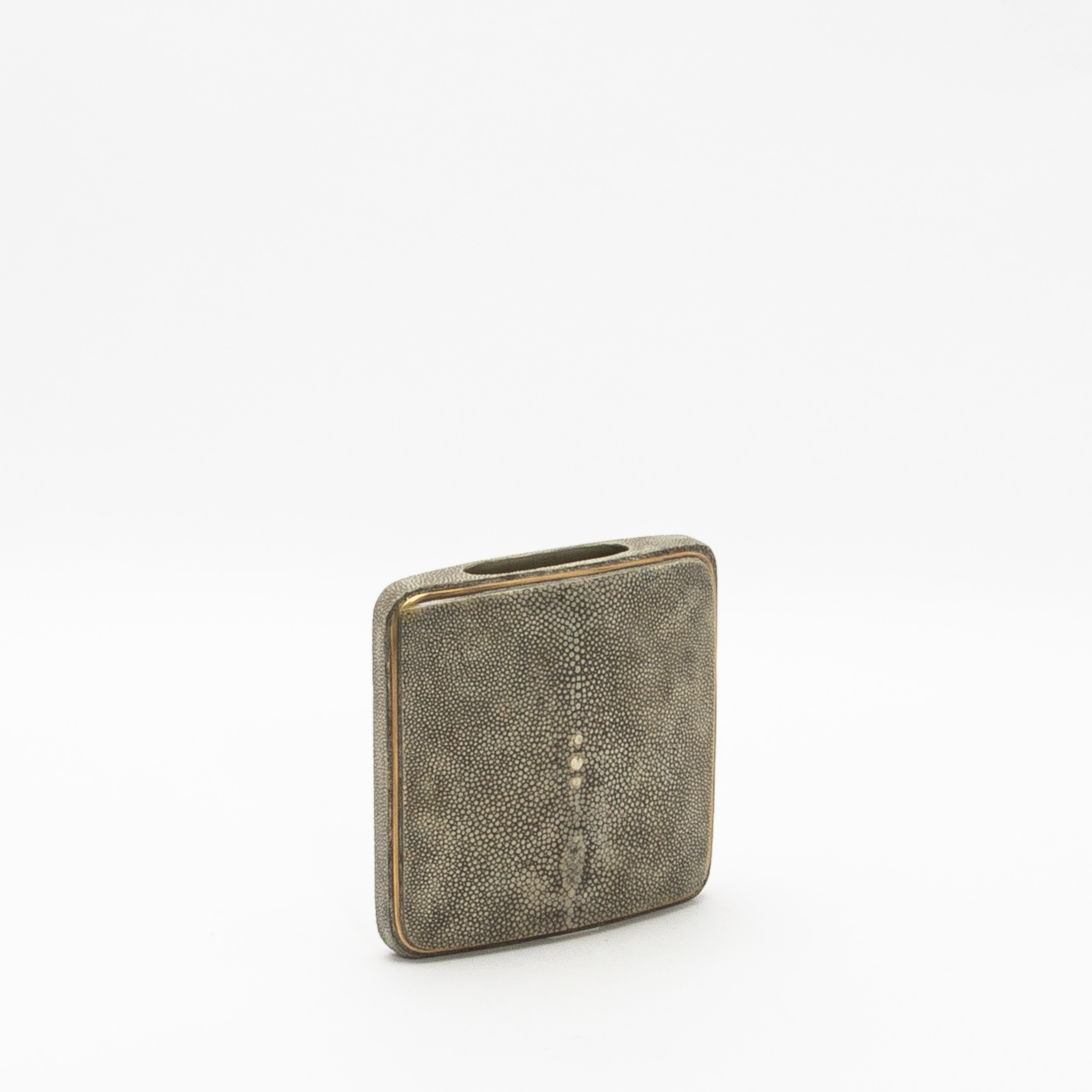 El Jarrón cuadrado de R&Y Augousti es una asombrosa fusión de elegancia moderna y meticulosa artesanía. Hecha a mano con lujoso shagreen, esta pieza se acentúa con sutiles detalles de latón que resaltan sus elegantes contornos. La superficie suave y