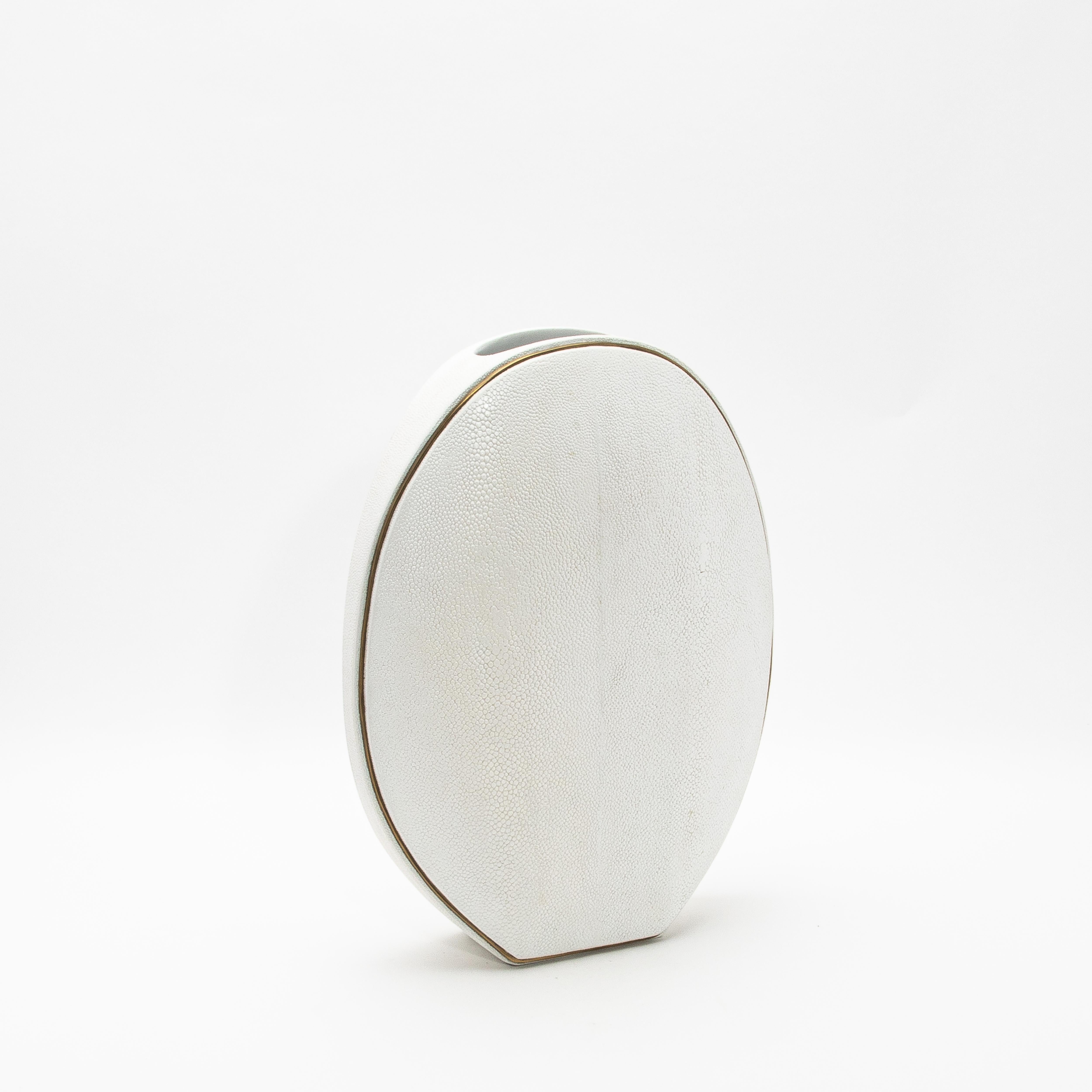 El elegante Jarrón Oval de R&Y Augousti, elaborado en piel de zapa y acentuado con latón, es una sofisticada fusión de textura orgánica y lujosos detalles. Su silueta ovalada presenta una forma llamativa, realzada por la meticulosa colocación de