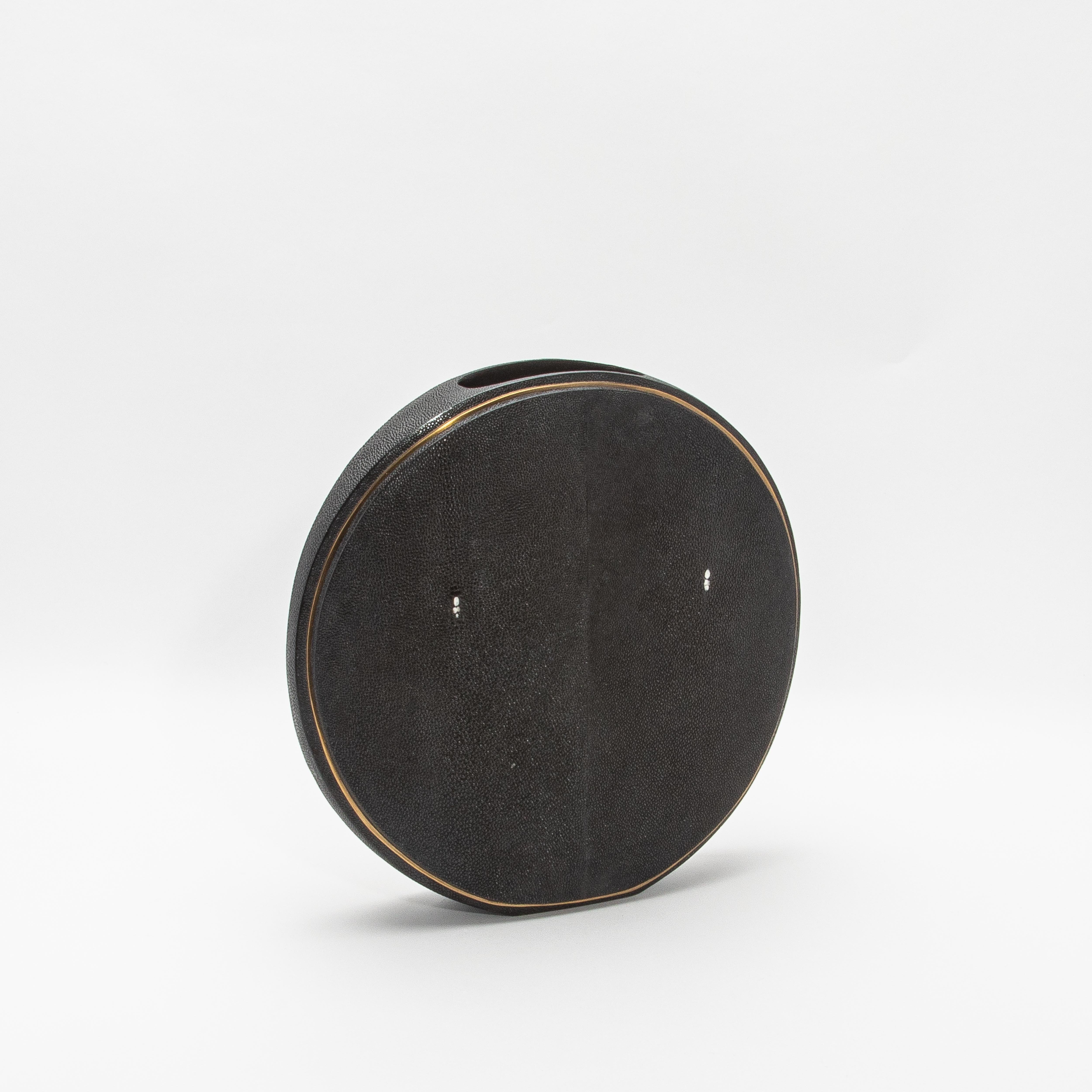 Este exquisito jarrón de R&Y Augousti captura la esencia de la artesanía con su lujosa superficie de piel de zapa, complementada con la elegancia de los detalles de latón acabados a mano. La forma redonda ofrece una silueta escultural y moderna,