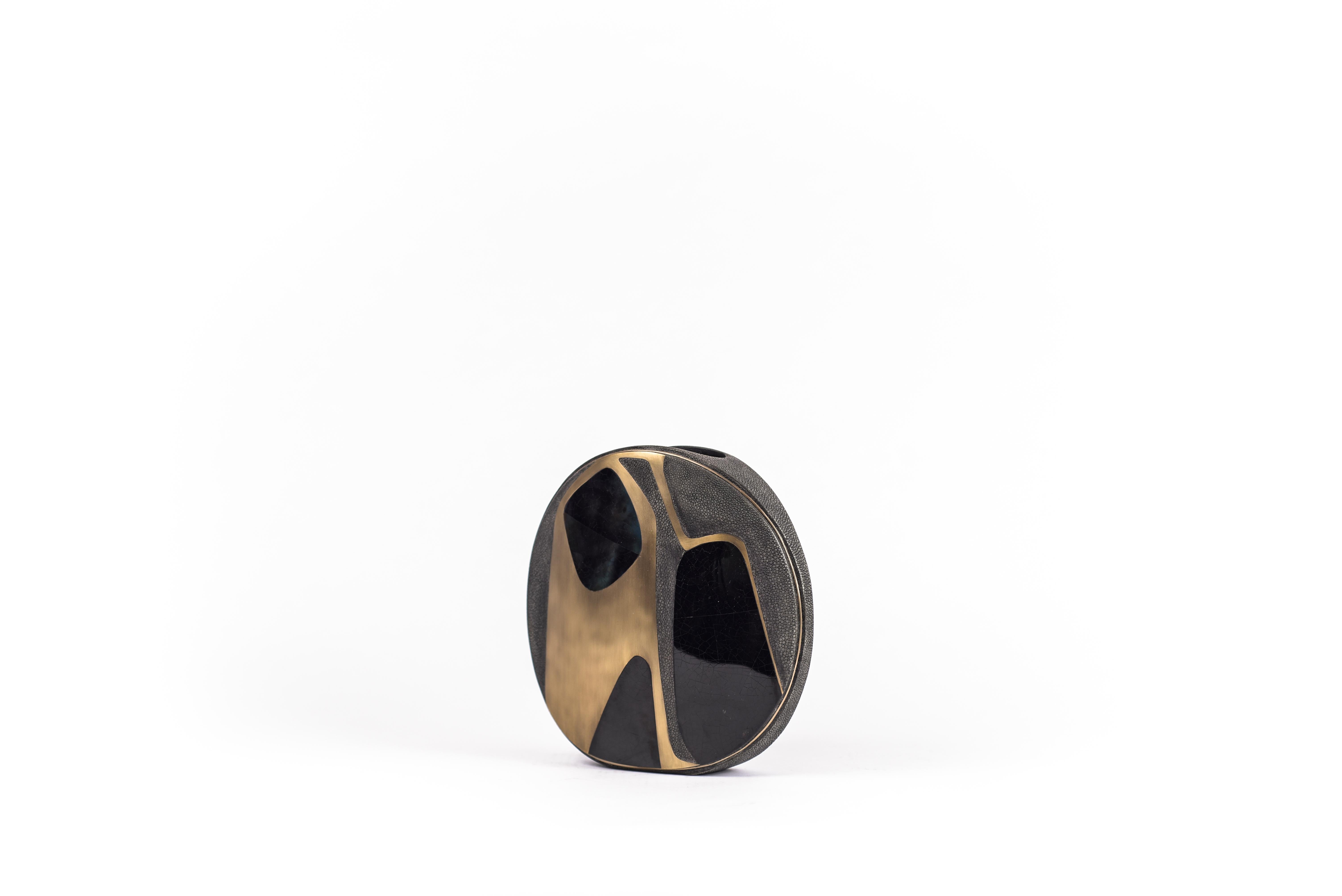 Die runde Vase Cosmos ist ein grafisches Stück, das jeden Raum aufwertet. Das kühne Muster ist in eine Mischung aus kohlschwarzem Chagrin, blauer Federmuschel und Bronze-Patina-Messing eingelegt. Die kreisförmige Vase ist mit einer Einbuchtung aus
