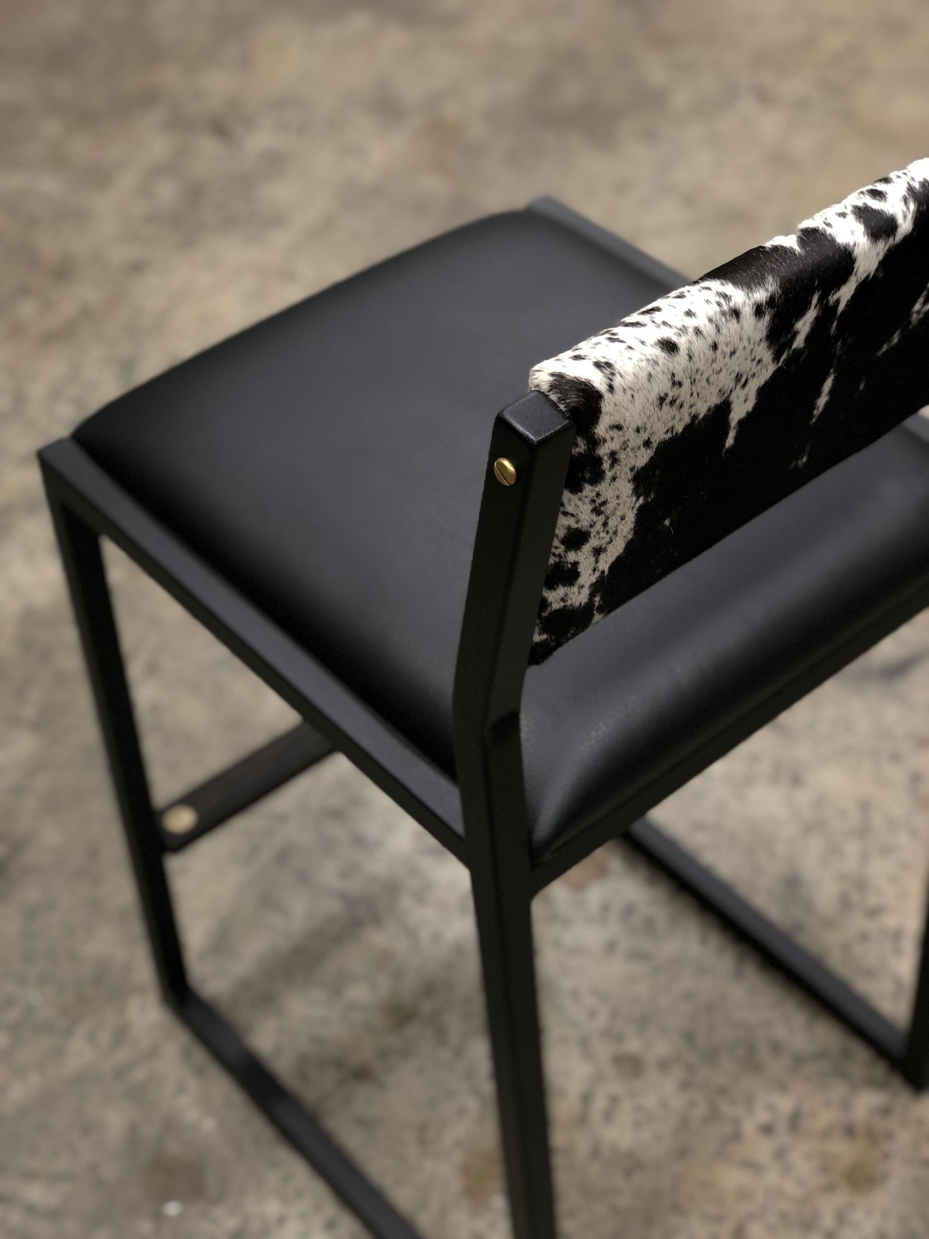 The shaker modern counter stool chair is handmade to order from our unique Ambrozia black textured steel tubing frame and a Genuine leather seat and a beautiful cowhide back. Also offered in COM or COL. Inspired by the boarding ladder steps of an