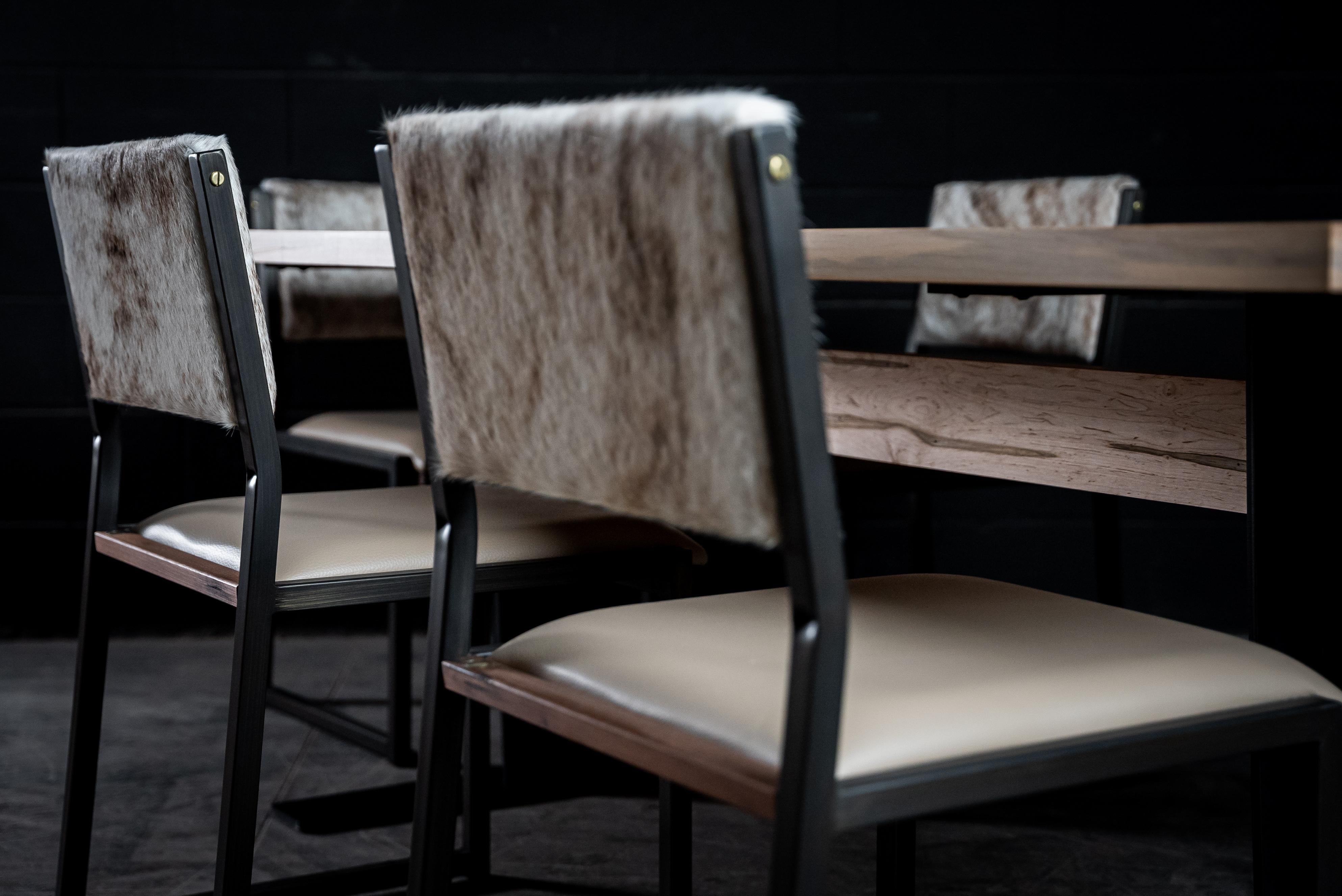 La chaise Shakers est fabriquée à la main sur commande à partir de notre cadre tubulaire unique en bronze brossé, avec un siège en cuir véritable et un dossier en cuir de vache. L'insertion subtile de bois massif donnera une touche chaleureuse et