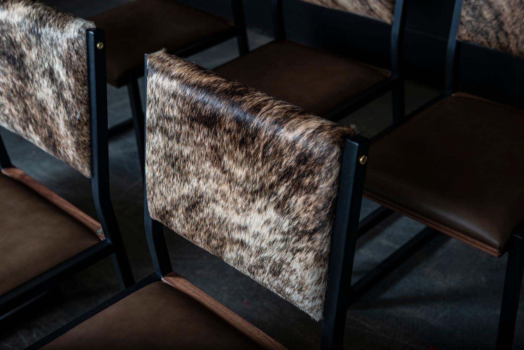 Cette chaise shaker est fabriquée à la main sur commande à partir de notre cadre unique en tubes d'acier texturé noir AMBROZIA, avec un siège en cuir véritable et un dossier en peau de vache. L'insertion subtile de bois massif donnera une touche