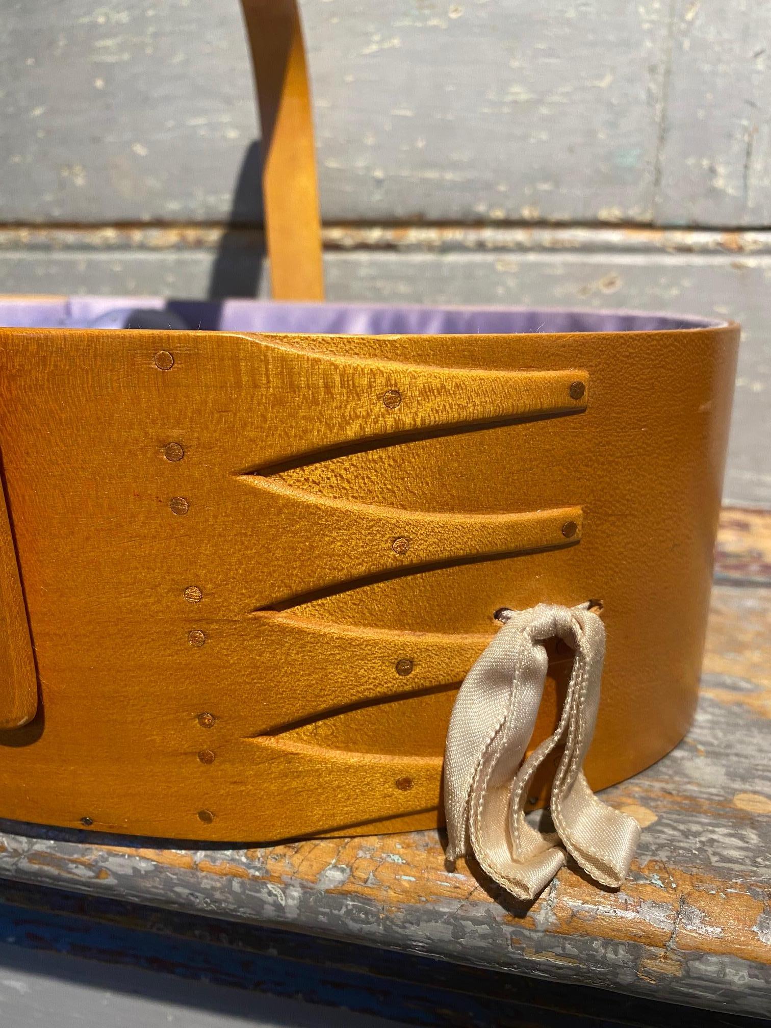 Early 20th Century Shaker Sewing Basket from the Sabbathday Lake Shaker Village in New Gloucester, Maine. An early oval band box made from split poplar with four finger laps and copper rivet fastenings, swing handle and original silk liner and