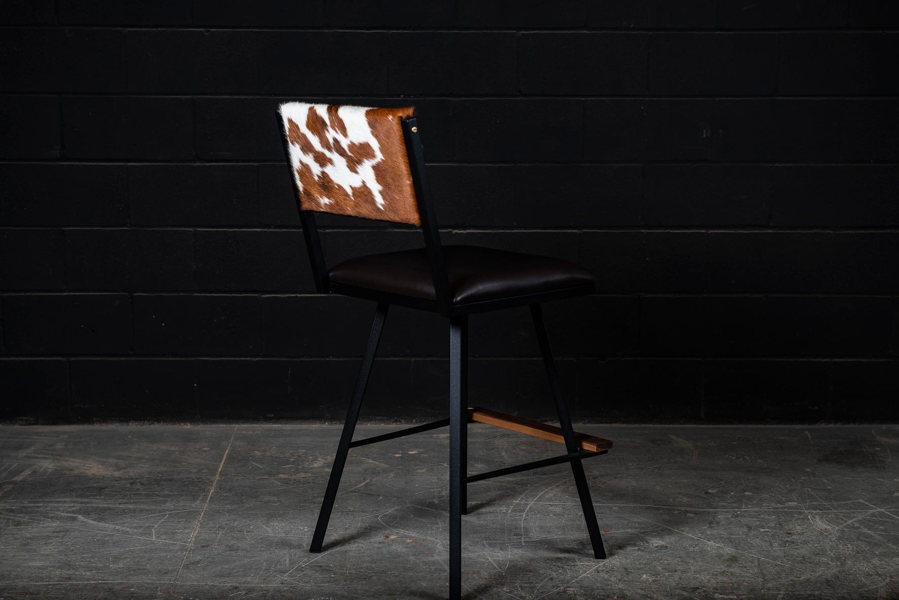 La chaise de bar pivotante Shaker est fabriquée sur commande à partir de notre cadre unique en tubes d'acier texturé noir AMBROZIA. Ce fauteuil pivotant contemporain / moderne est disponible dans une grande variété de cuirs véritables, de vinyles,