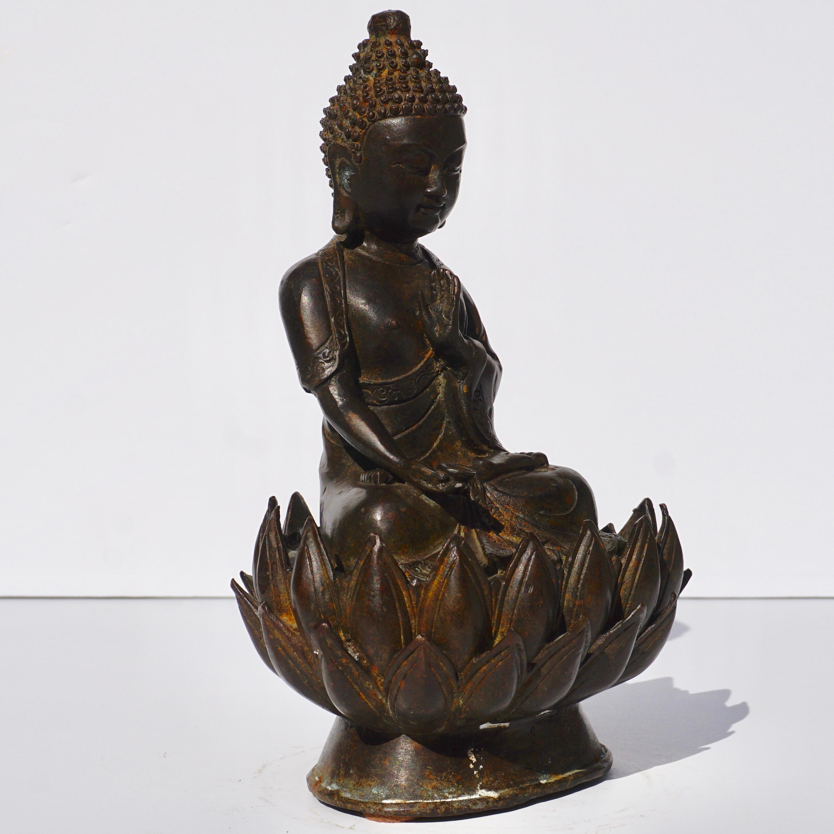 A Chinese bronze medicine Buddha figure, Qing Dynasty, 19th century. The Buddha is seated in dhyanasana on a lotus flower base with the right hand in dhyanamudra holding a bowl filled with myrobalan fruit, and the left hand close to the heart chakra